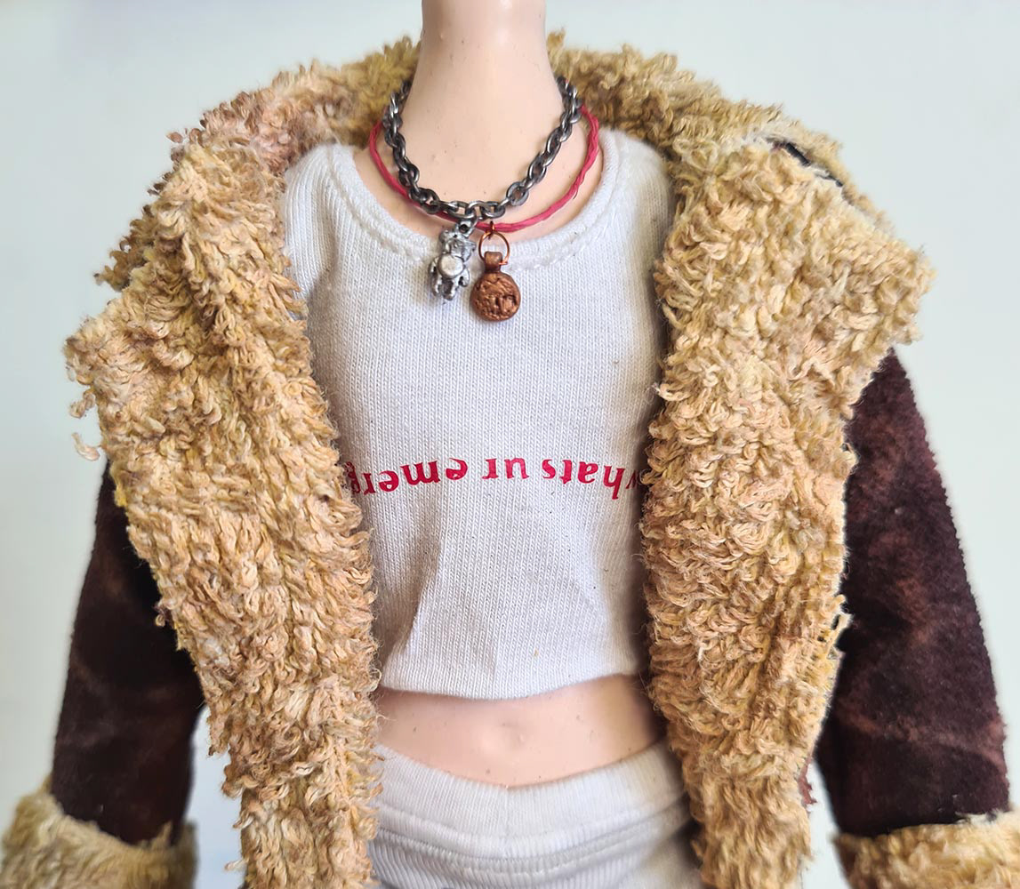 The necklaces and charms on the puppet of Rhian.