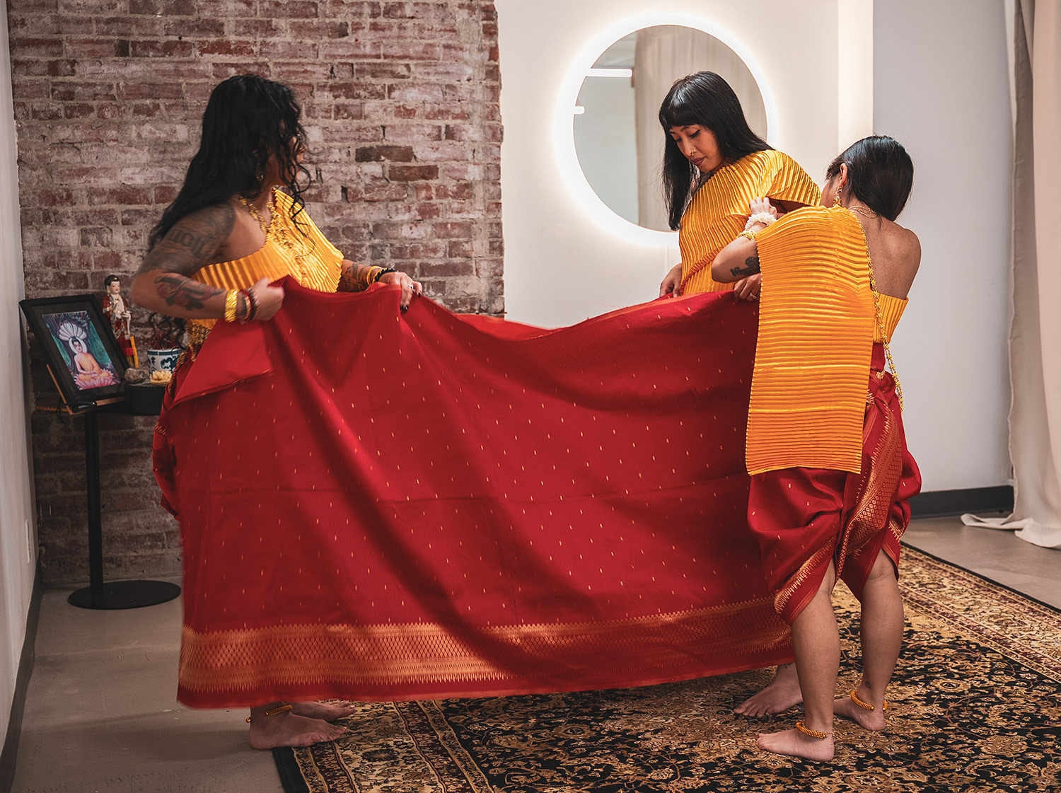 Dancers help each other unravel and stretch the red cloth worn for their traditional garb. 