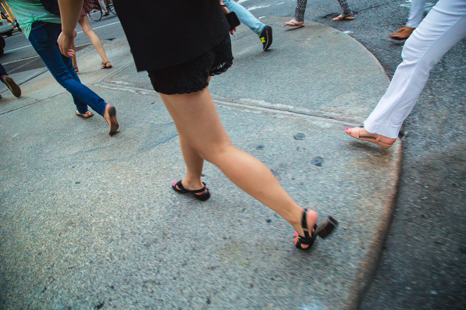 Men and Women Stride through Crosswalk in New York City