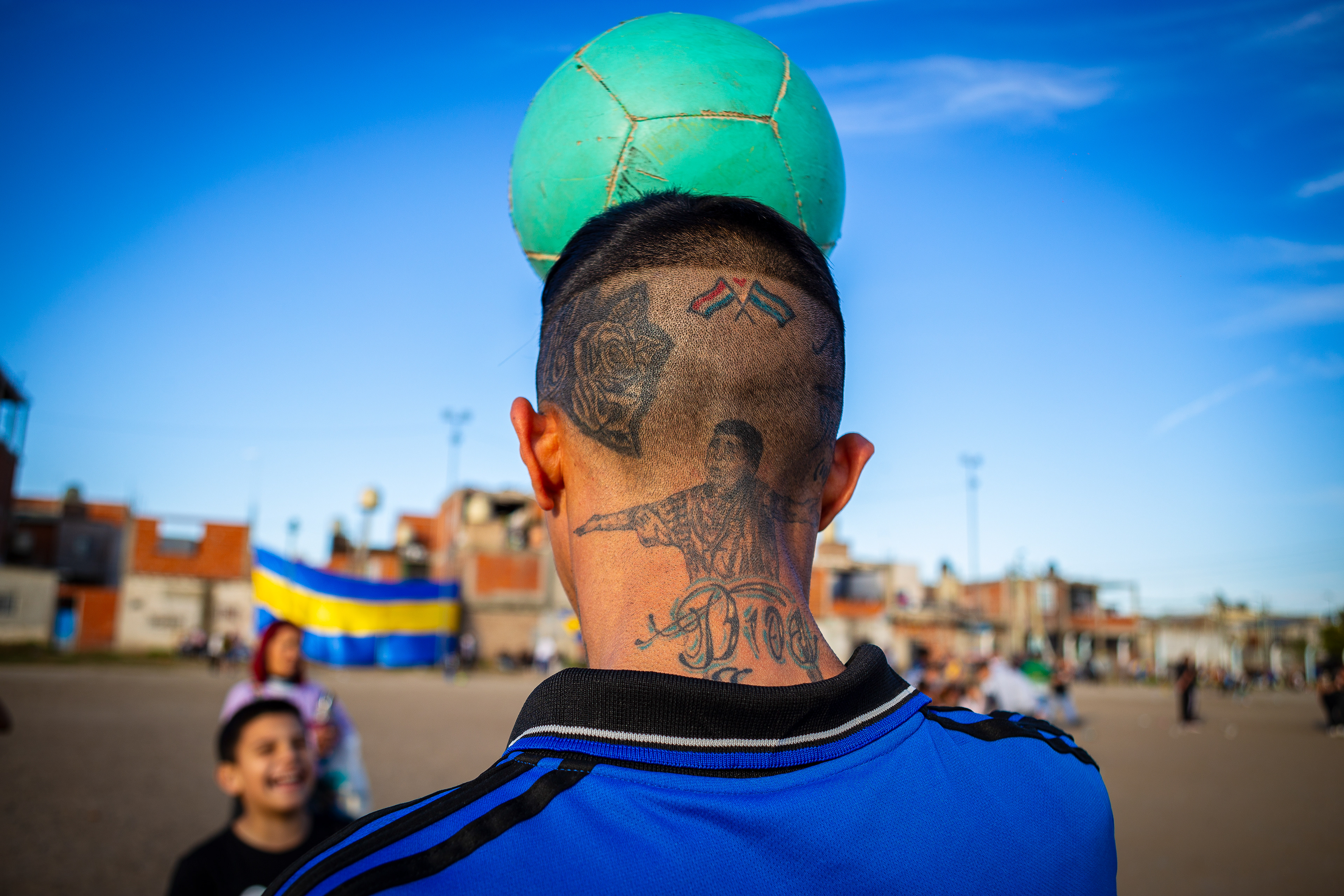 A local resident known as "Chavito" juggles a football in front of his son at "El Potrero de D10S," the pitch where football legend Diego Armando Maradona grew up playing in Villa Fiorito, Buenos Aires province, Argentina. September 8, 2024. (Photo by Catriel Gallucci Bordoni)
