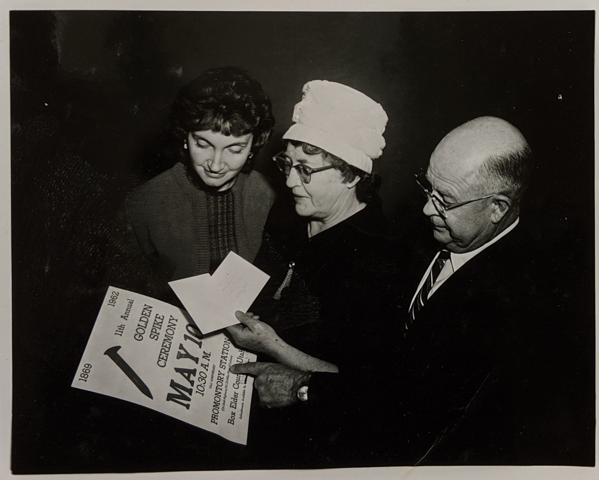 Delone Glover, Bernice Gibbs Anderson & man look at the Golden Spike poster for 1962 commemoration. Bernice Gibbs Anderson Collection, NPS