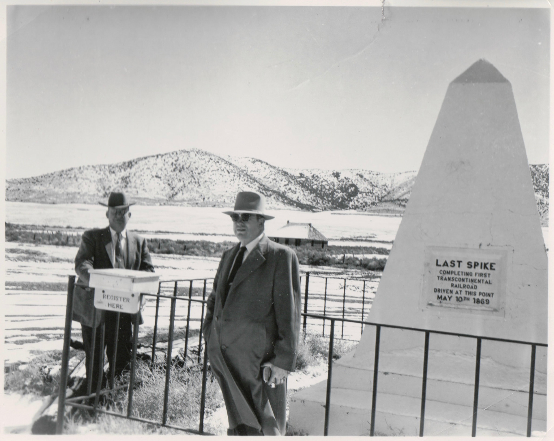 Two men in suits visiting the Golden Spike obelisk monument, Golden Spike Site, Promontory Summit, Utah. Bernice Gibbs Anderson Collection, NPS