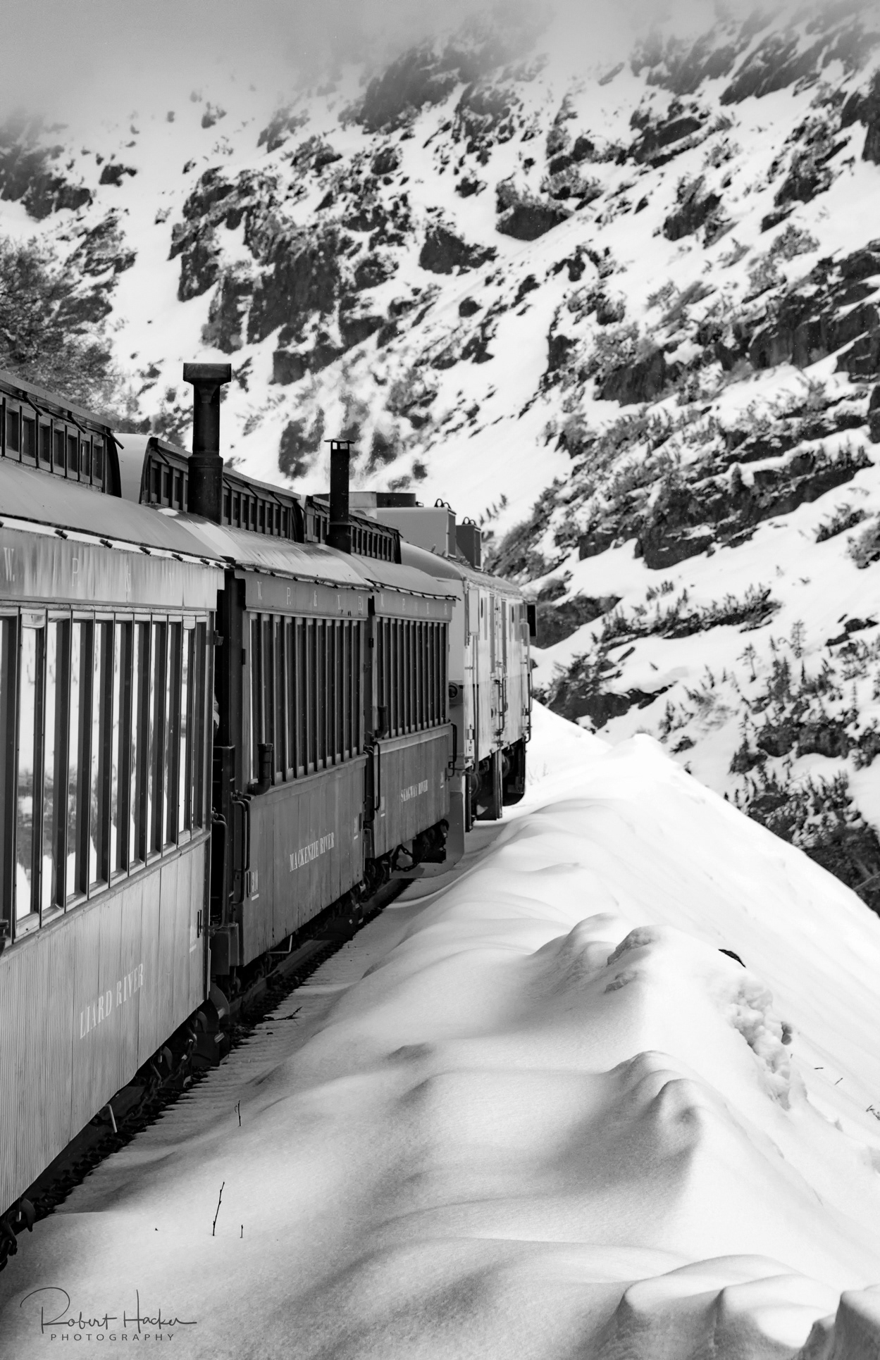 View of a snow field and the train taken from between cars on the White Pass & Yukon Route Railway