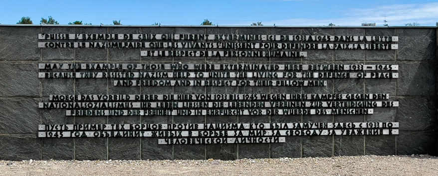 This monument states the purpose of the Dachau Concentration Camp Memorial Site in four languages. The statement in english says "May the example of those who were exterminated here between 1933-1945 help to unite the living for the defence of peace and freedom and in respect for their fellow man."