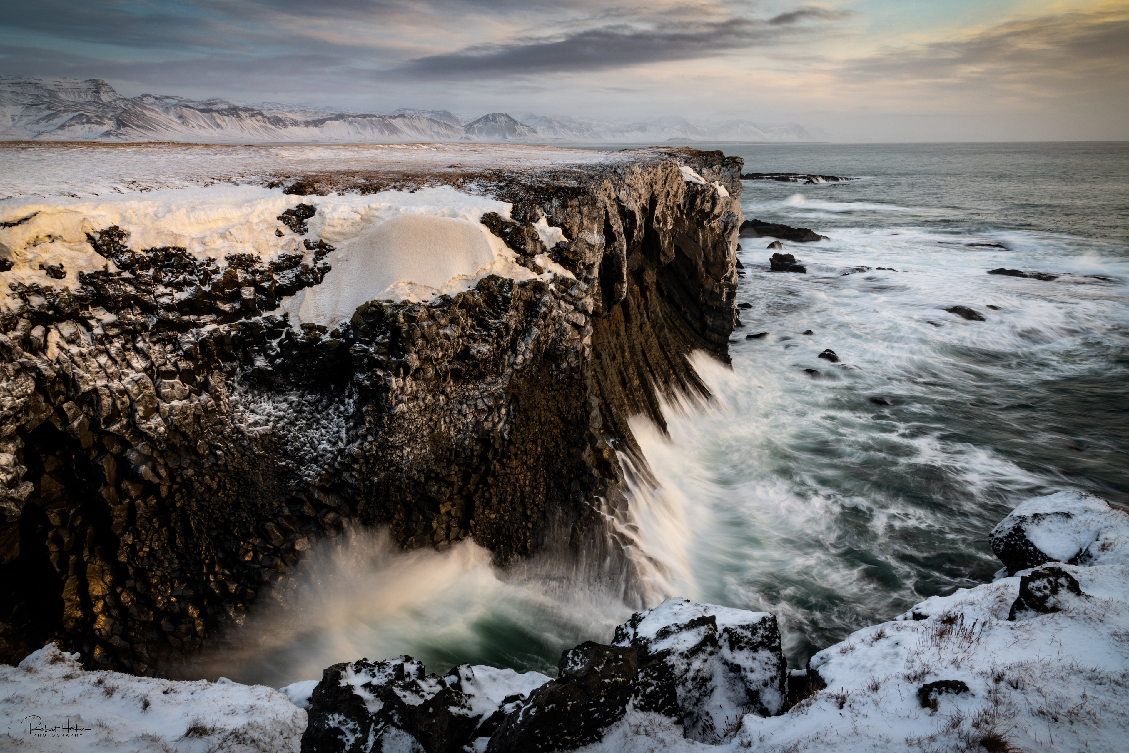 Basalt cliffs at Arnarstapi.  The sun had just risen above the cloud cover to bathe the cliffs with warm light