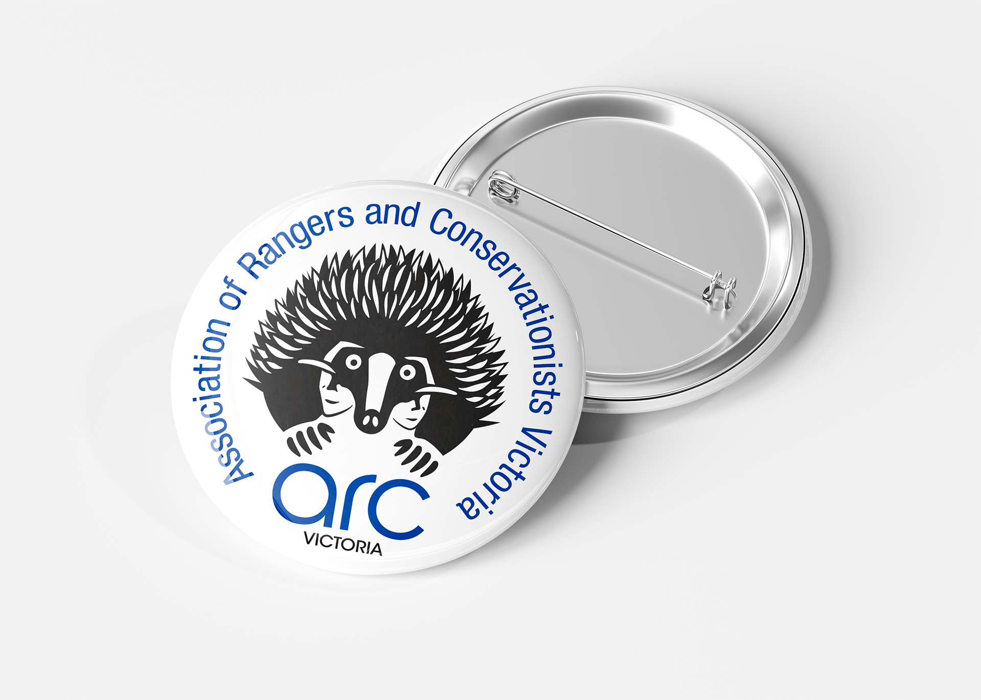 ARC Victoria button badge in two colour, black brandmark and blue type.