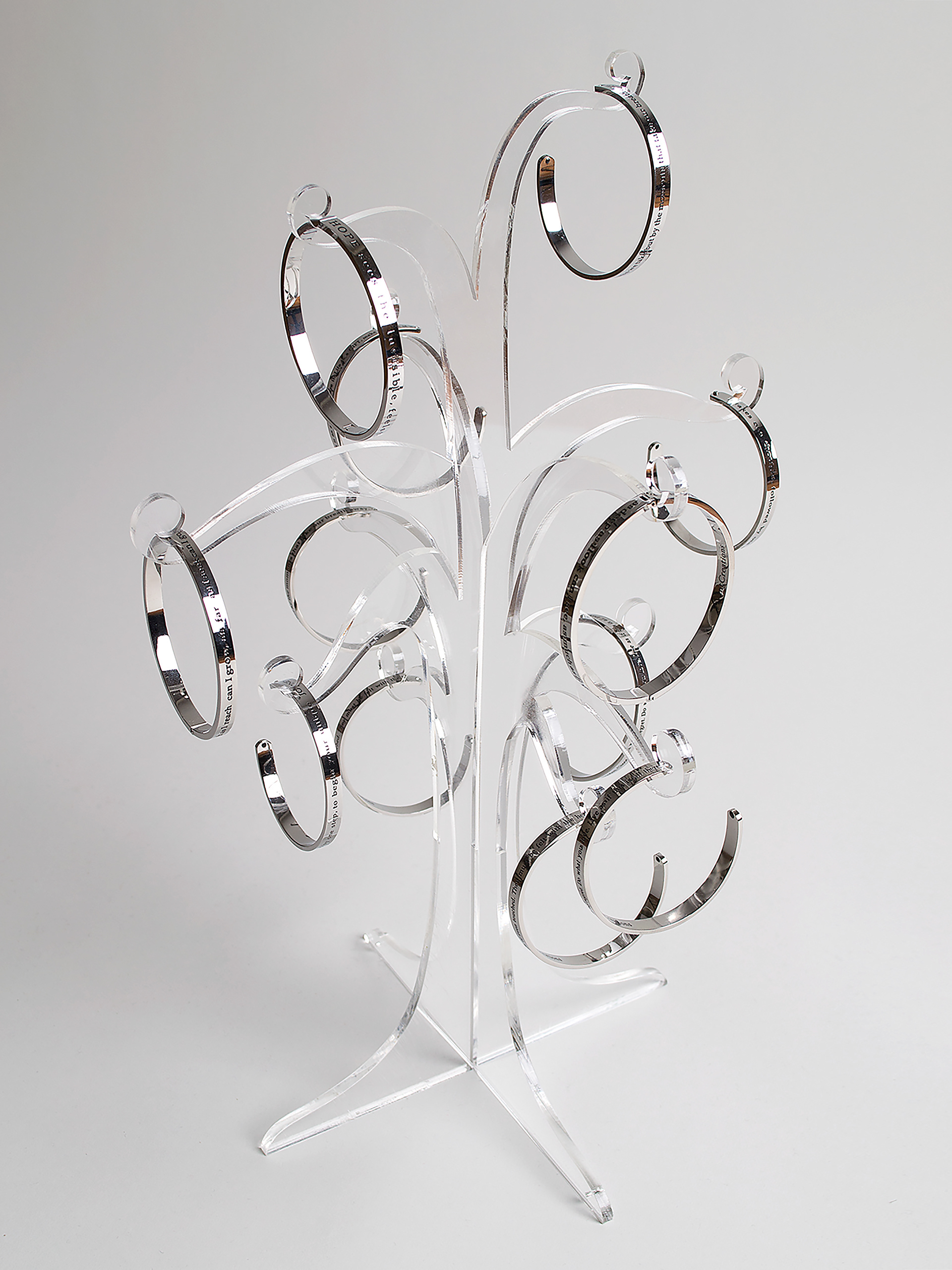 Clear acrylic tree shaped jewellery stand displaying silver bracelets.