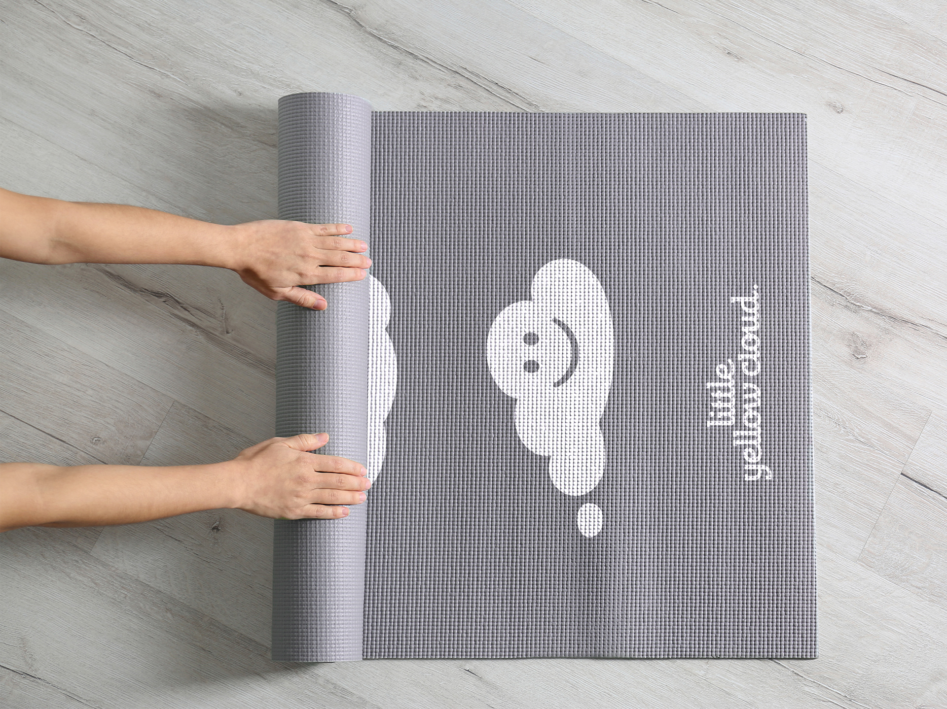 Hand rolling out yoga mat, revealing Little Yellow Cloud branding.
