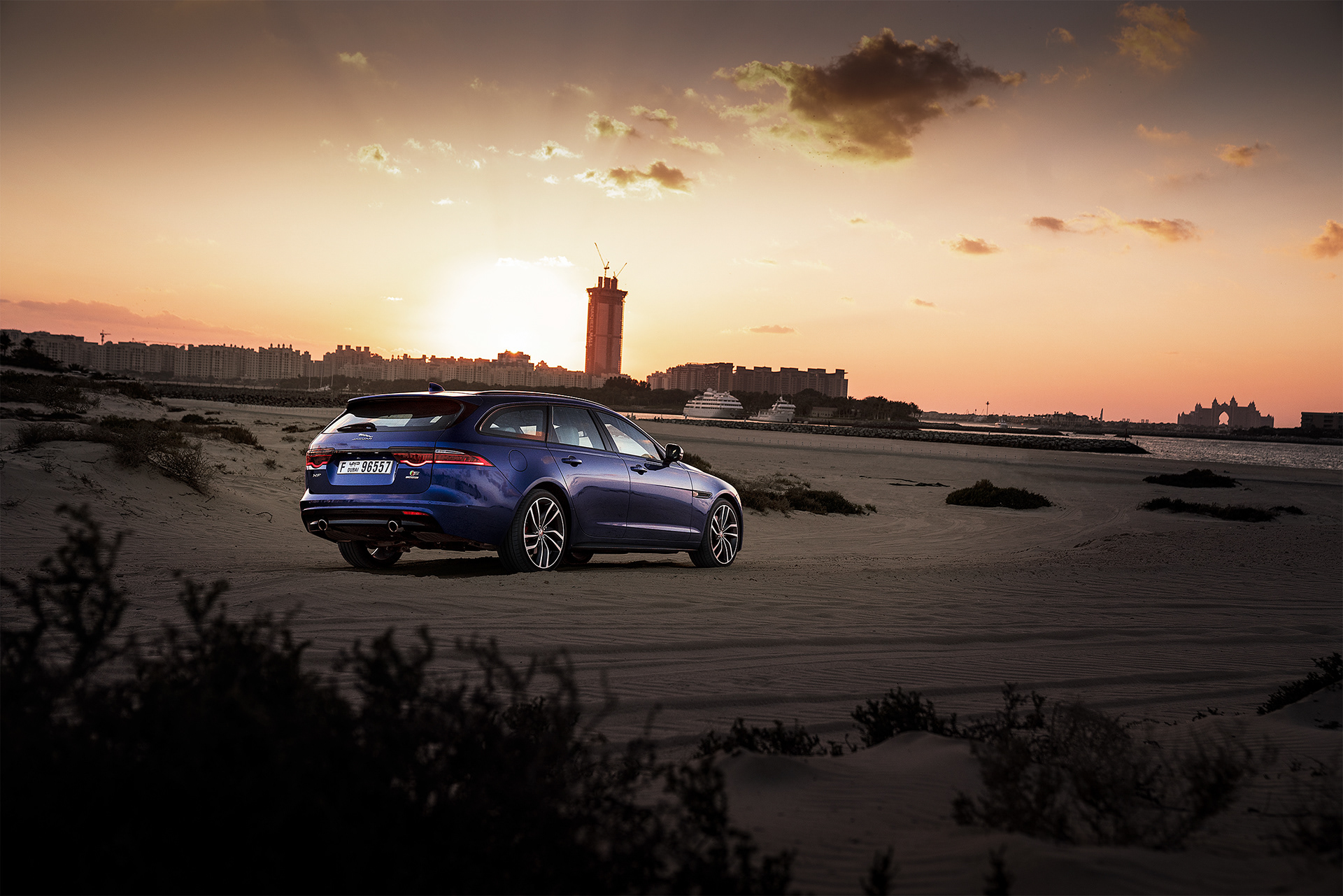 Jaguar sedan car on a beach at sunrise.