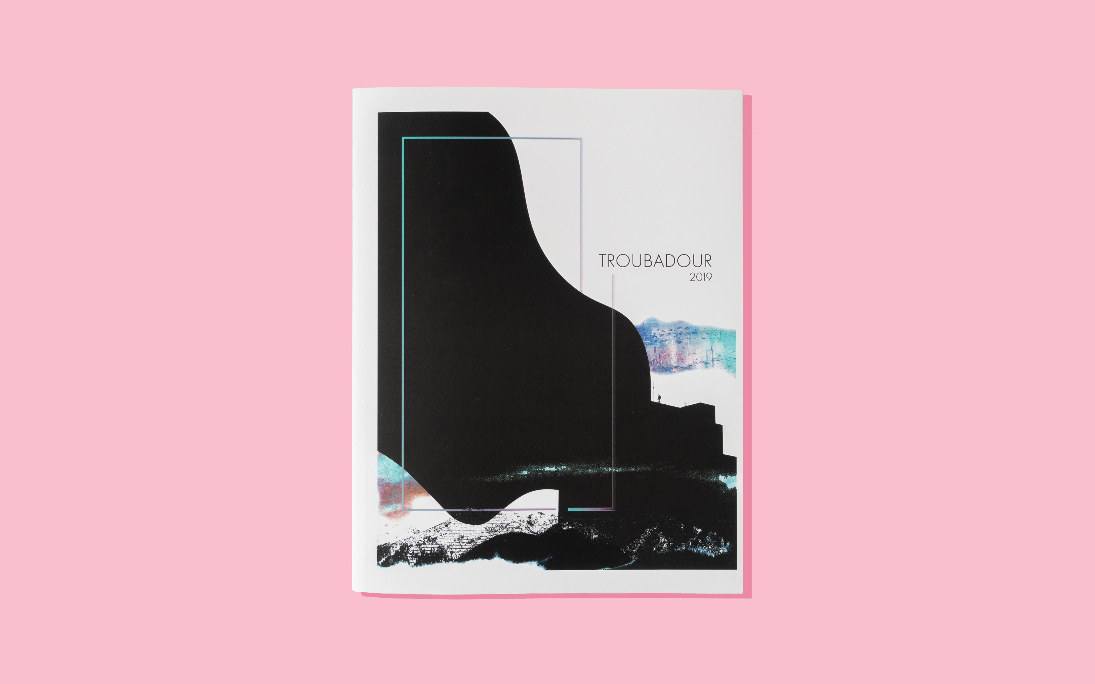 The front cover of a print copy of the Troubadour 2019 book in front of a pink background.