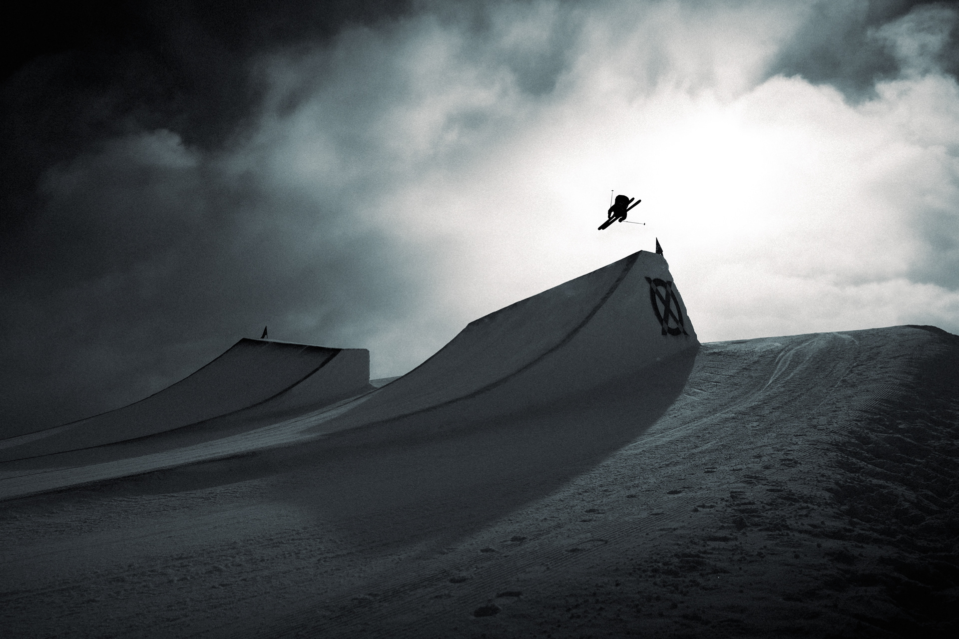 Ben Barclay is silhouetted agains a cloudy, but sun pierced sky during the Laax Open Ski Slopestyle