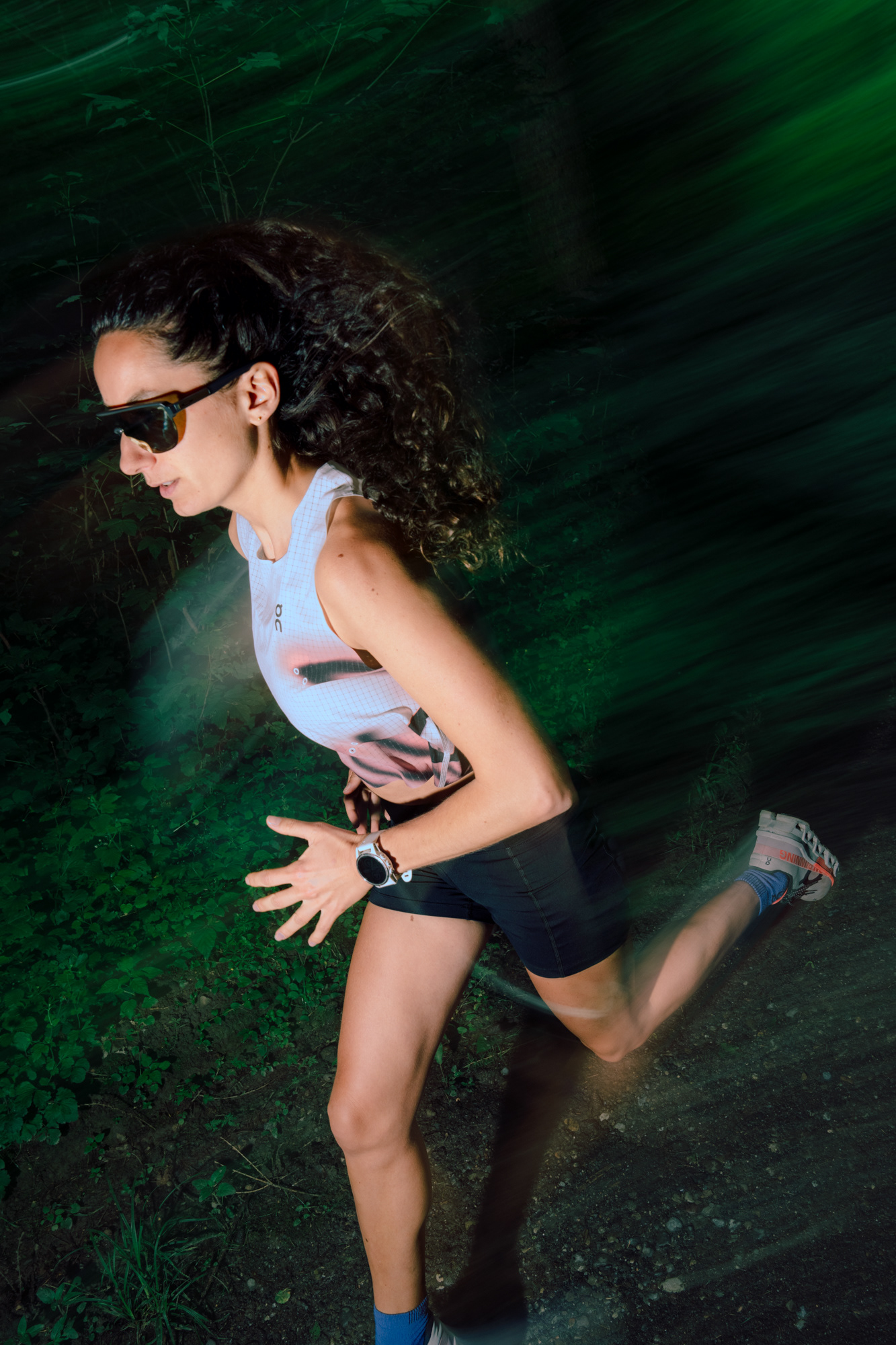 A female Runner on a dirt path in the forest. The runners motion is captured with some blur.