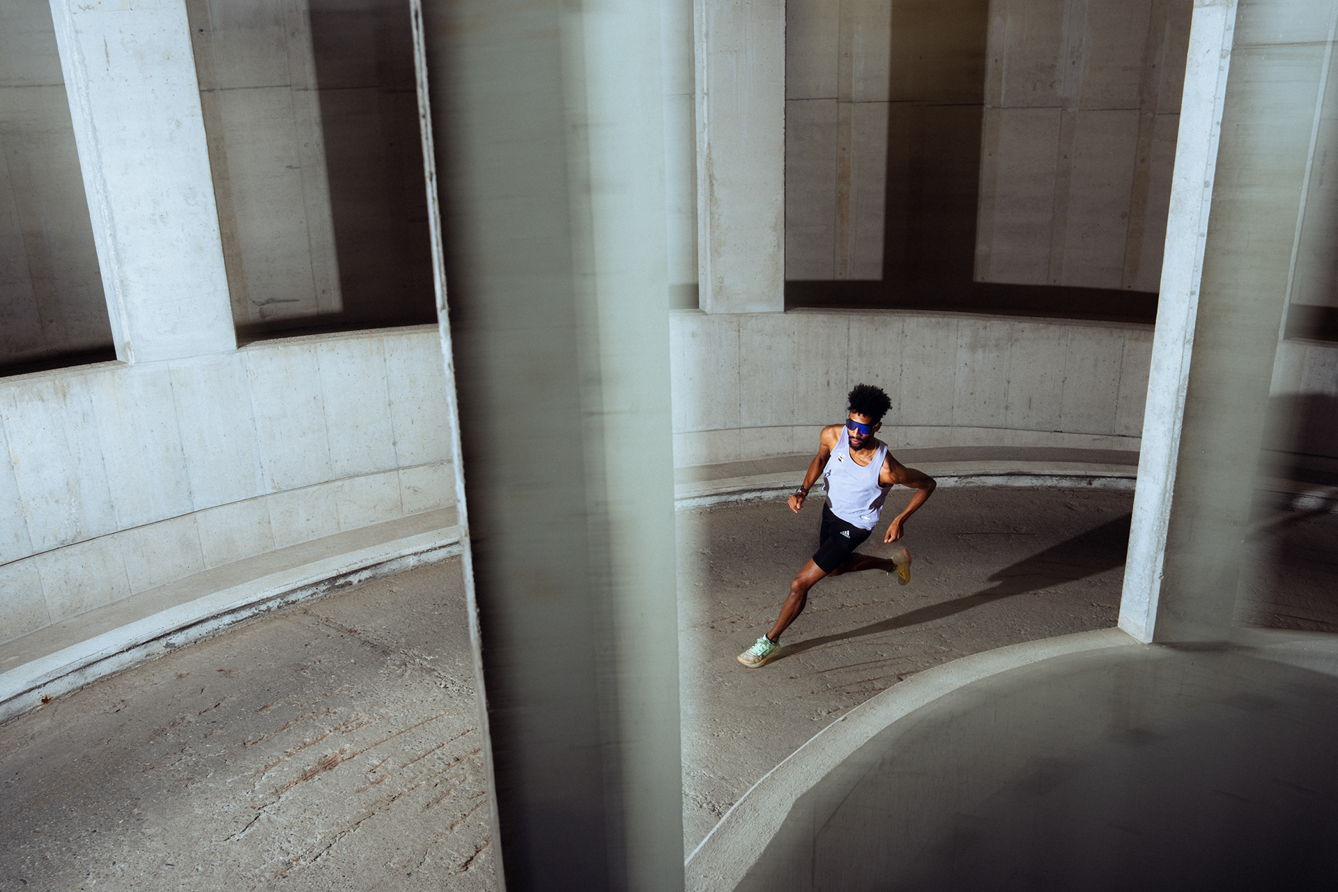 athlete running up a spiral ramp. the photograph exudes energy through a slow shutter speed. the subject is colorful amidst a concrete structure.
