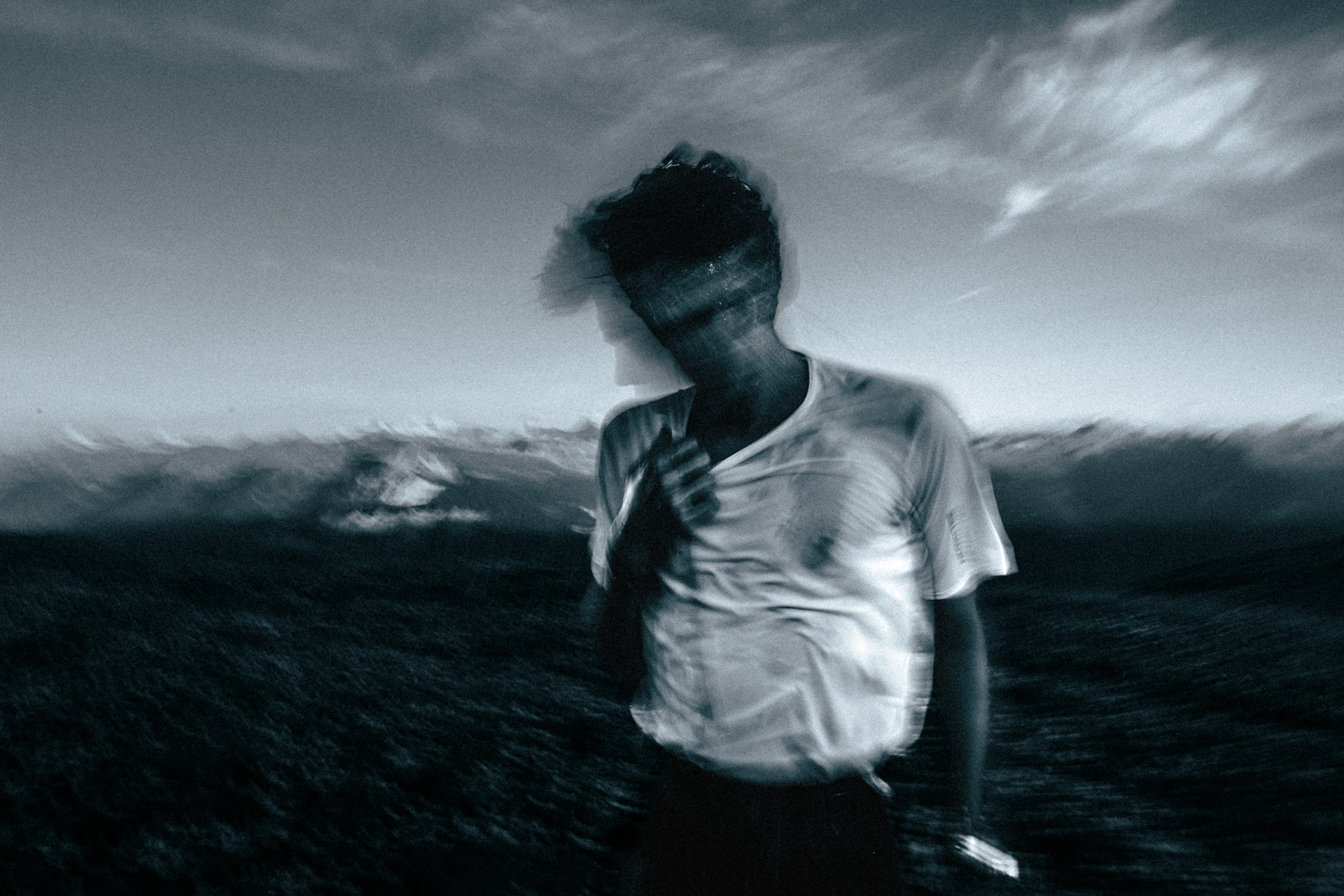 Black and White photograph with motion. Runner shaking water from hair infant of a mountain backdrop