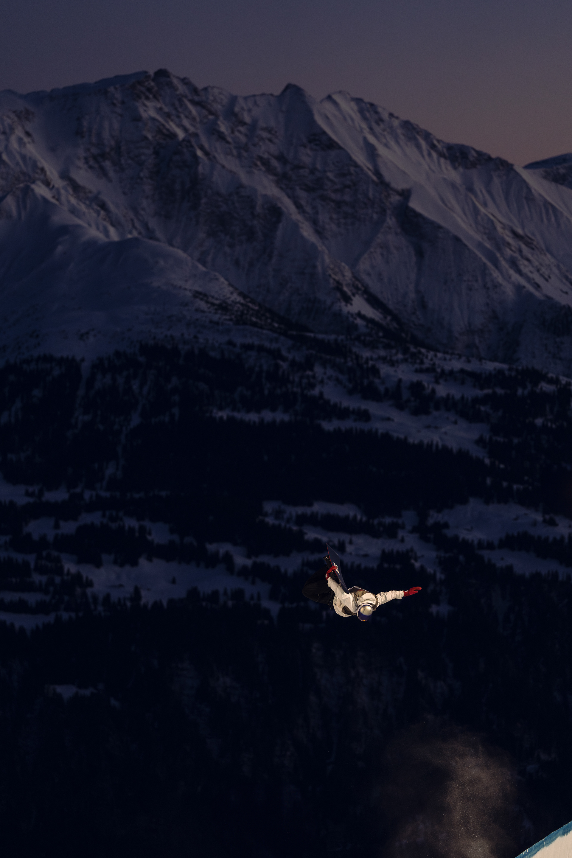 Scotty James going huge out of the Halfpipe, infront of the alps glowing purple in the last light, during the Laax Open . Red Bull, Laax,