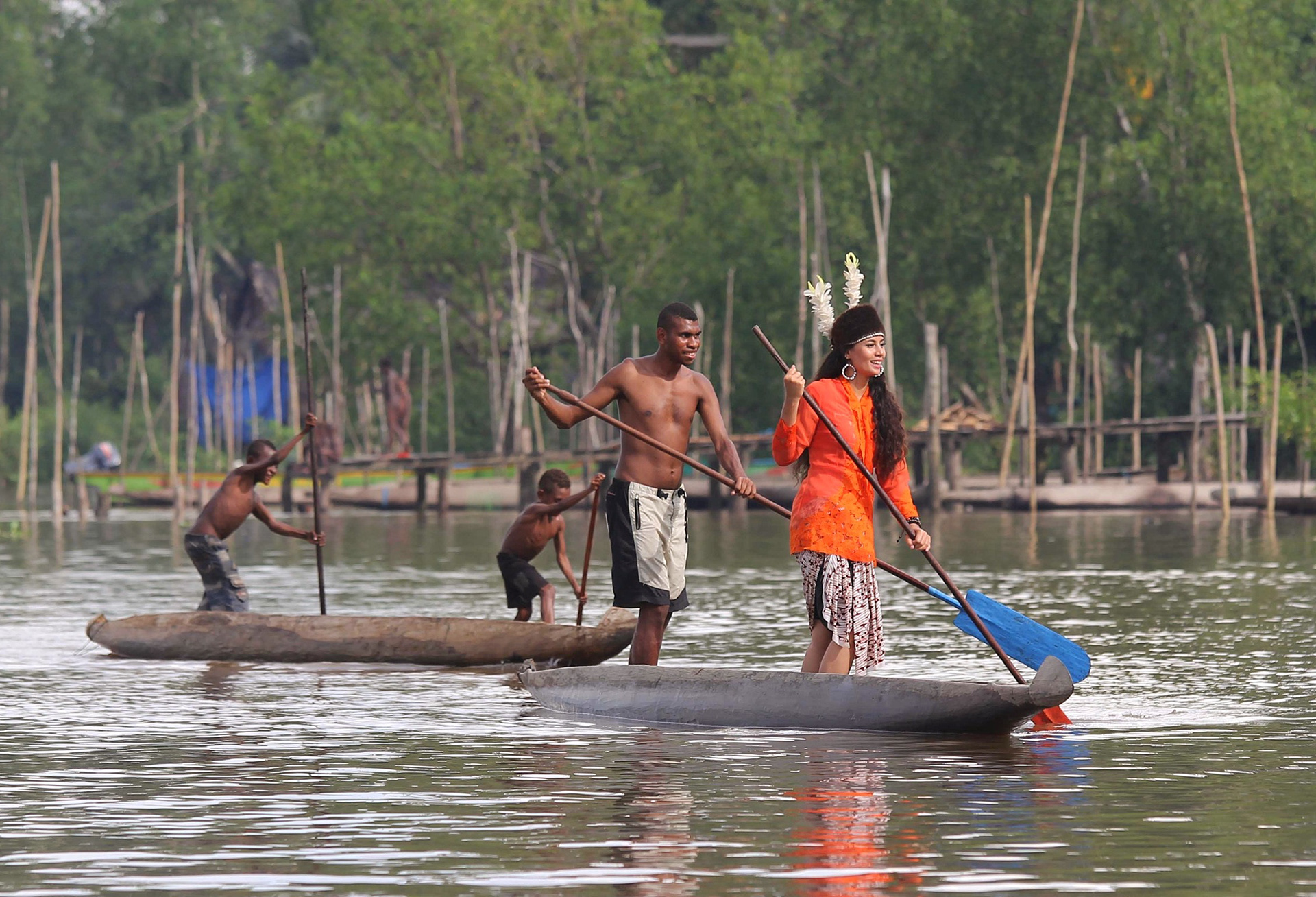Fiona Callaghan in Kebaya wearing Pacin and rowing a traditional Asmat boat in Kampung Atsj, Asmat