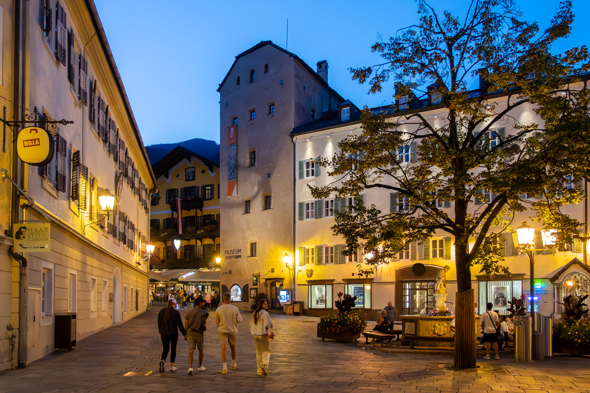 Evening street lamps illuminate the with Vogt Tower and fountain in Zell am See, Salzburg, Austria