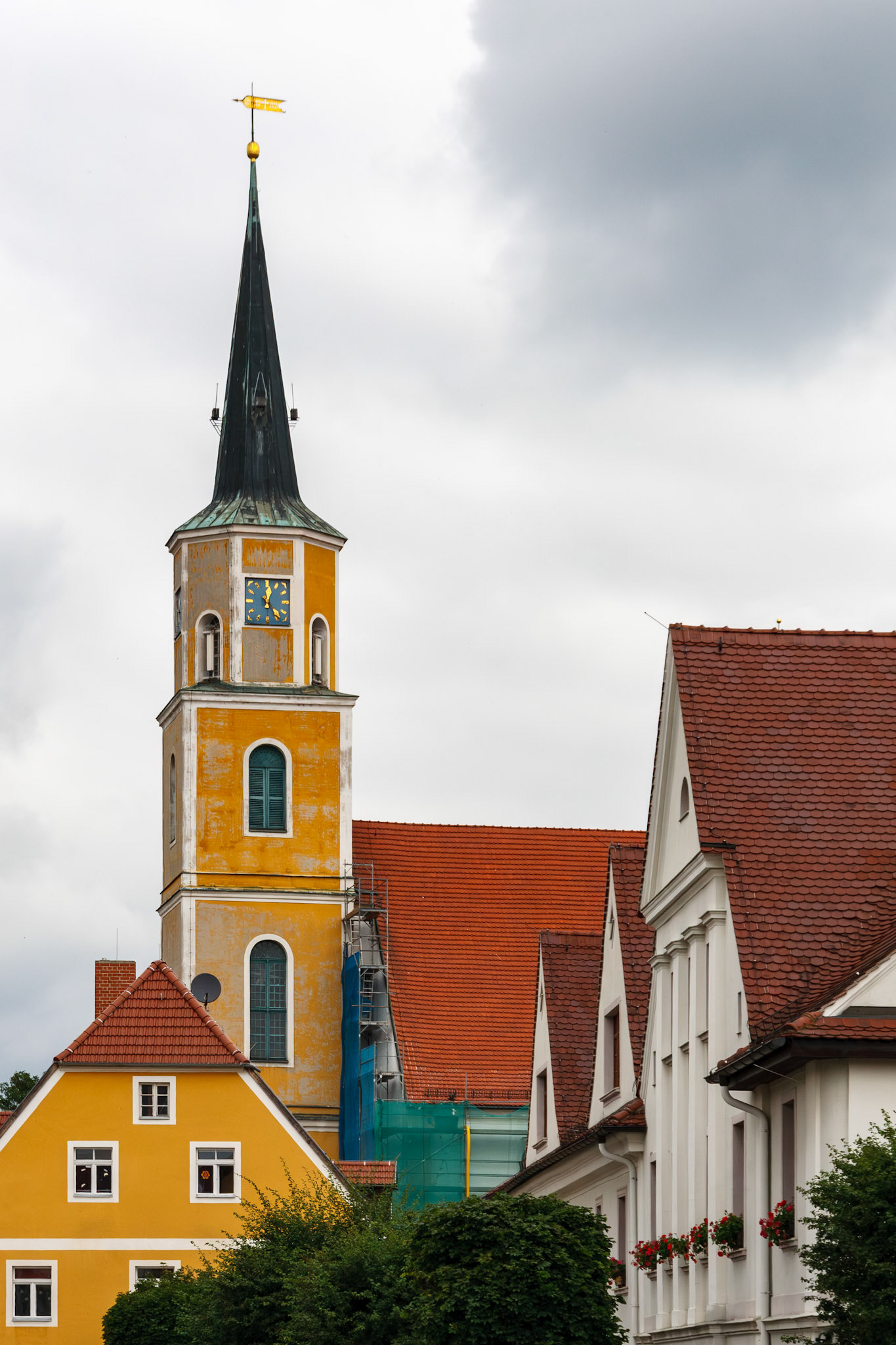 Historic yellow church tower rising above buildings