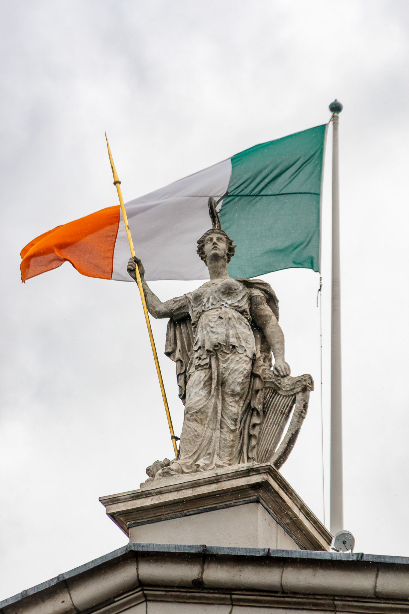Statue holding a flag against a cloudy sky