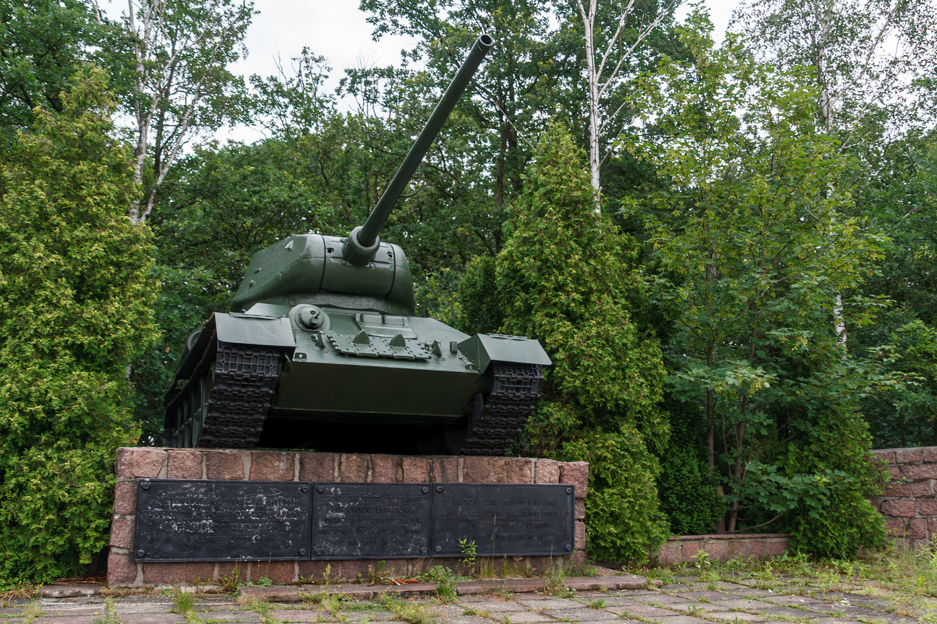 Military tank monument surrounded by green trees