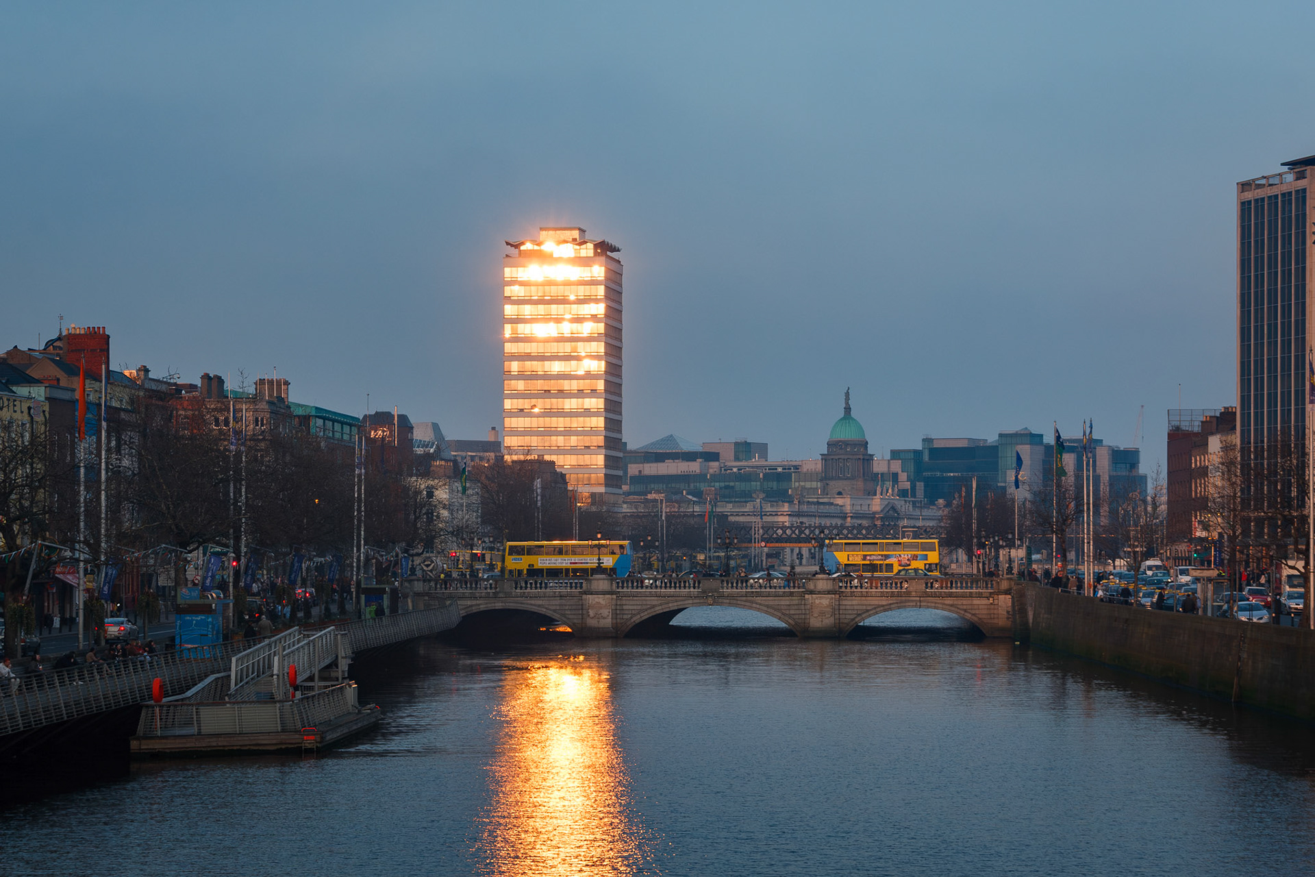 Skyscraper reflecting golden sunset over river