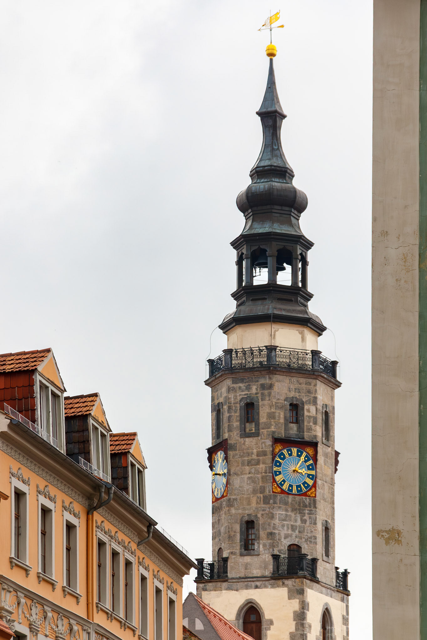 Stone clock tower with ornate blue dials