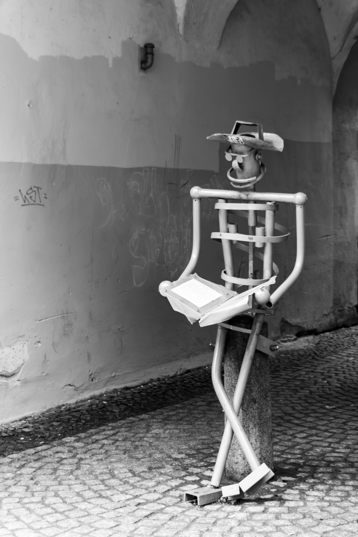 Metal stick figure sculpture reading a book