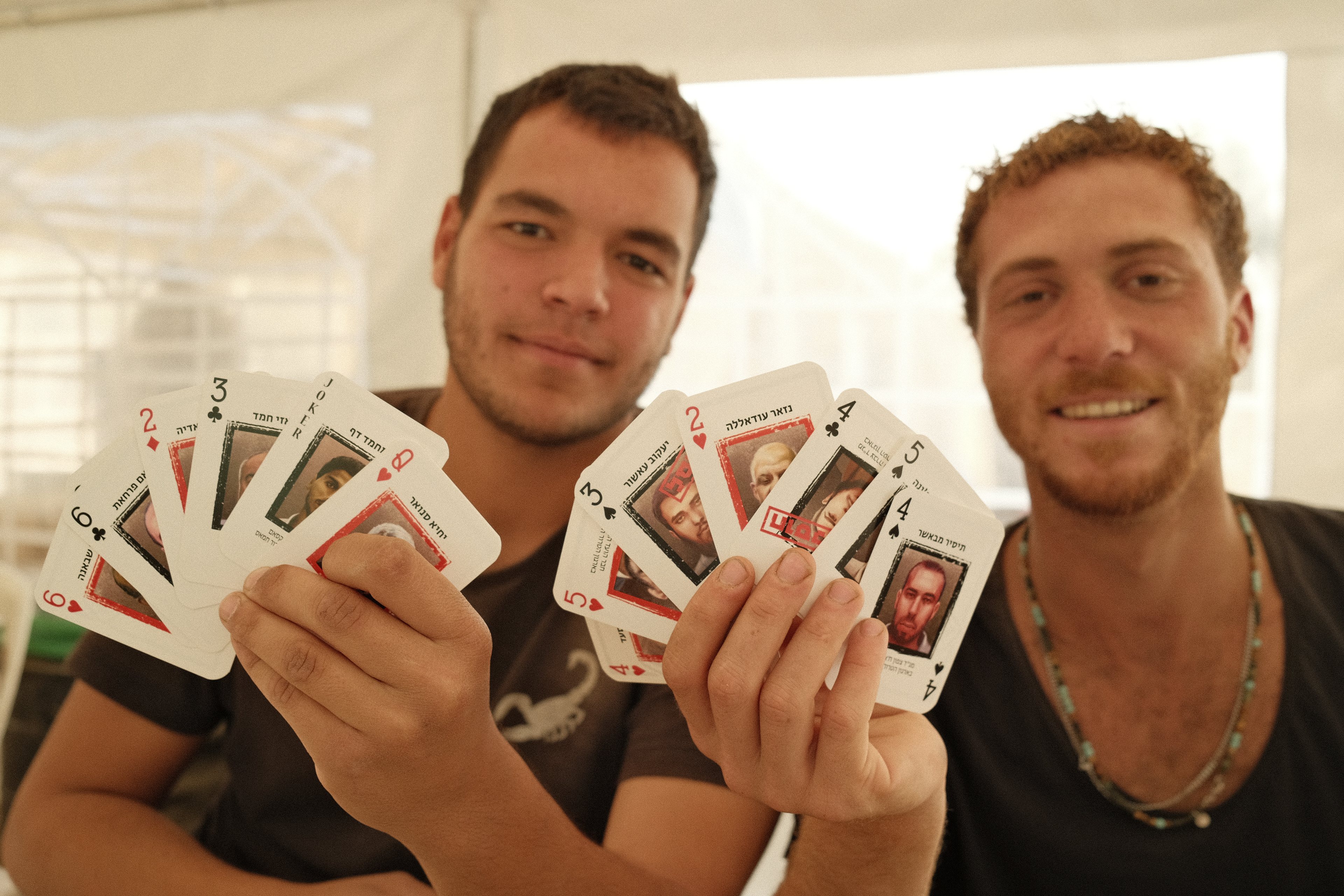 Guy and Guy, holding playing cards with Hamas terrorists drawn on them