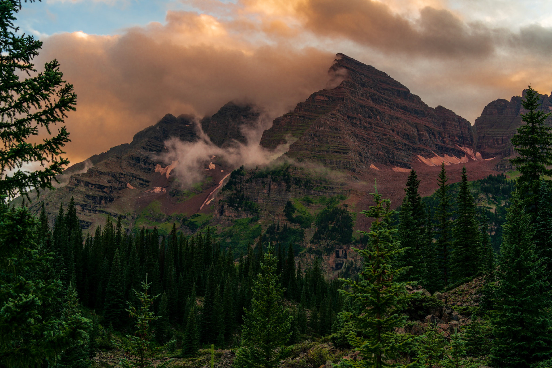 As a rather prolific rainstorm began to retreat, I noticed how the Maroon Bells began to come into my view. The longer I stood before these mountains, the better the light became before the sun eclipsed the horizon and the moody scene was over.