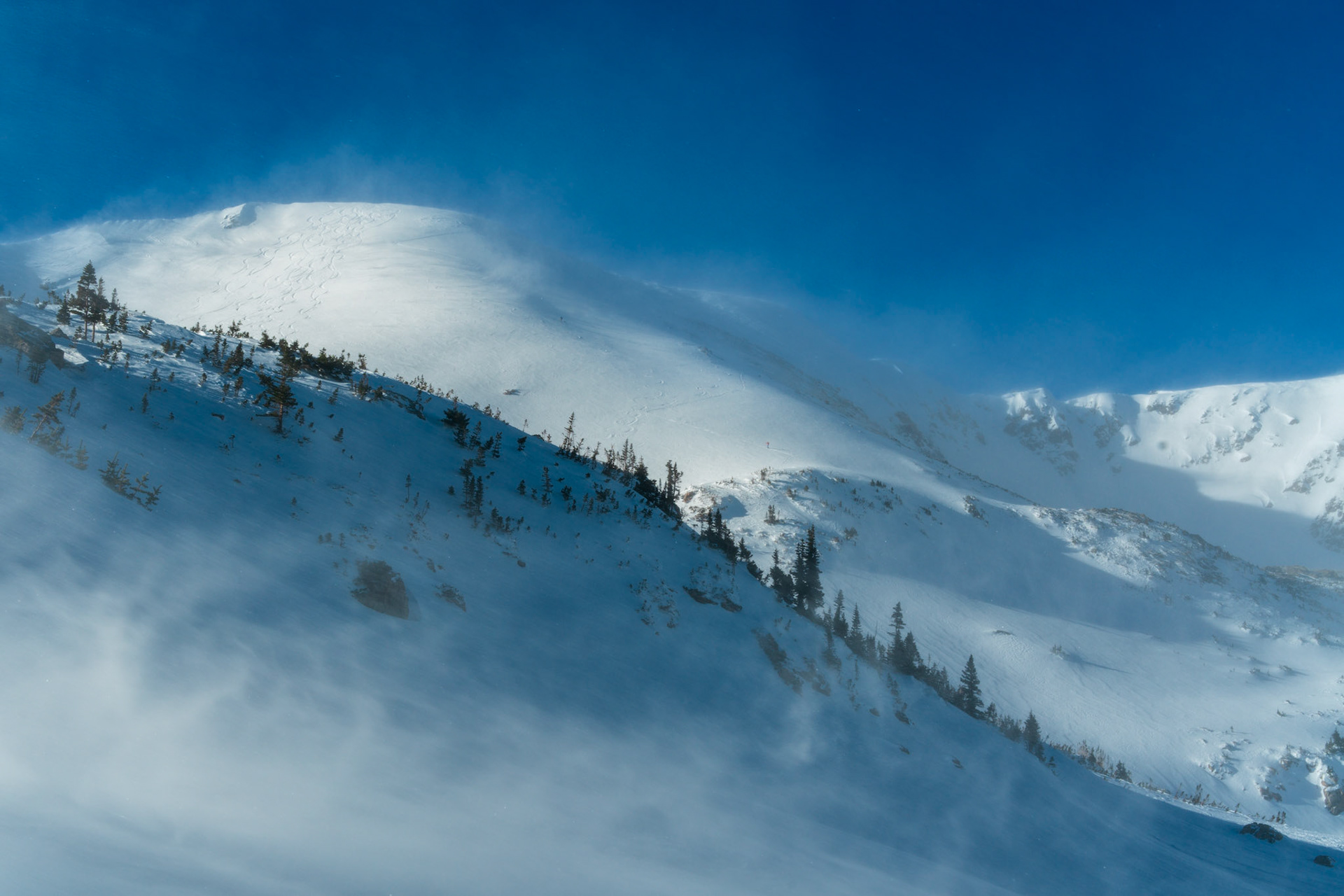 It was a blue bird day high in the Arapaho and Roosevelt National Forest, but also a breezy one. When I came to a ridge above treeline, I noticed that I was not alone. A pair of skiers were skinning up to the summit of the Continental Divide before me. I really enjoyed how they provided scale in this divine, but moody scene.