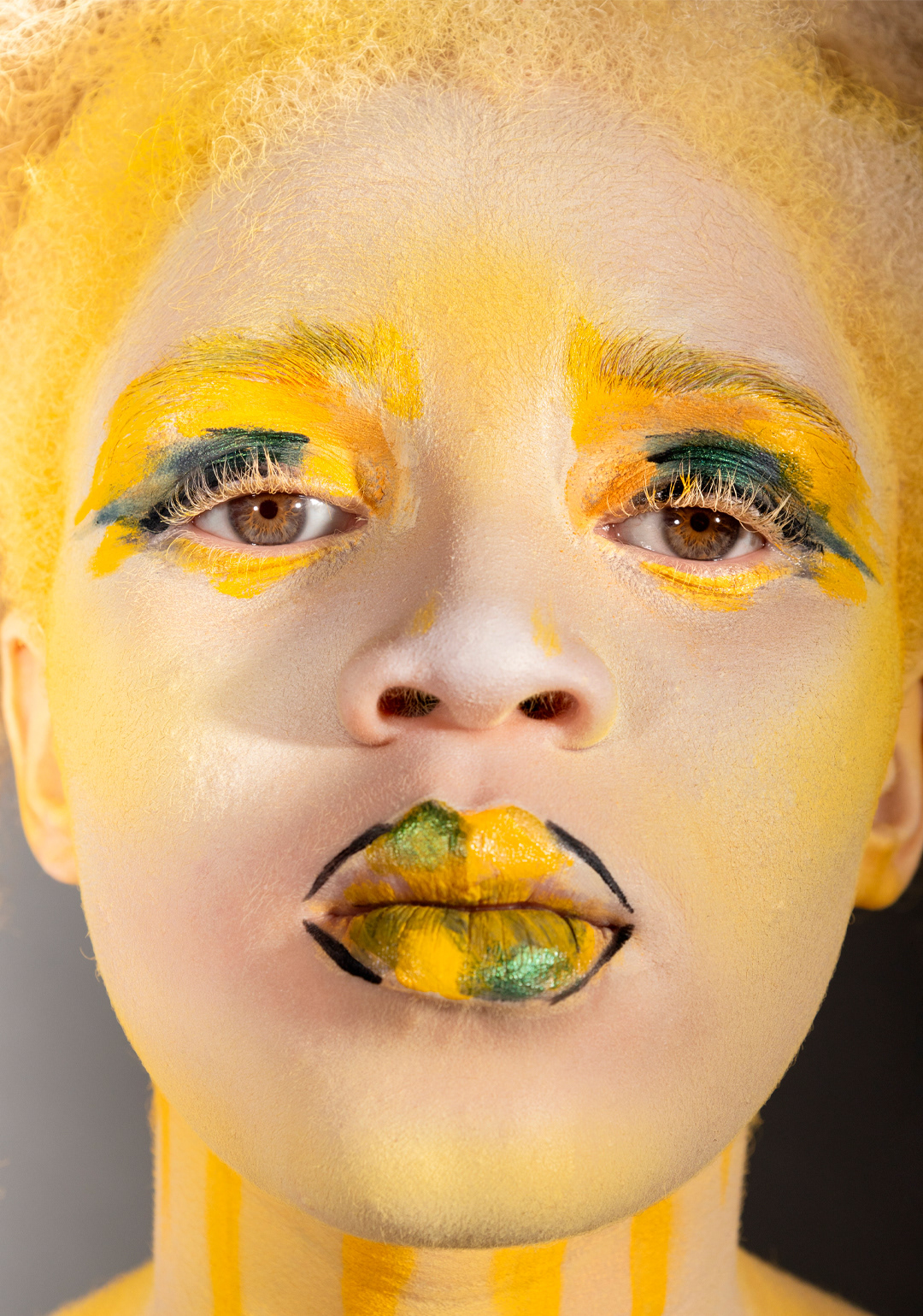 Primer plano de modelo albina con ojos claros, mostrando el rostro y parte del cuerpo pintado con body painting que simula ropa africana tradicional. Detalles artísticos en manos y torso, destacando la cultura africana y el arte corporal sobre piel clara.