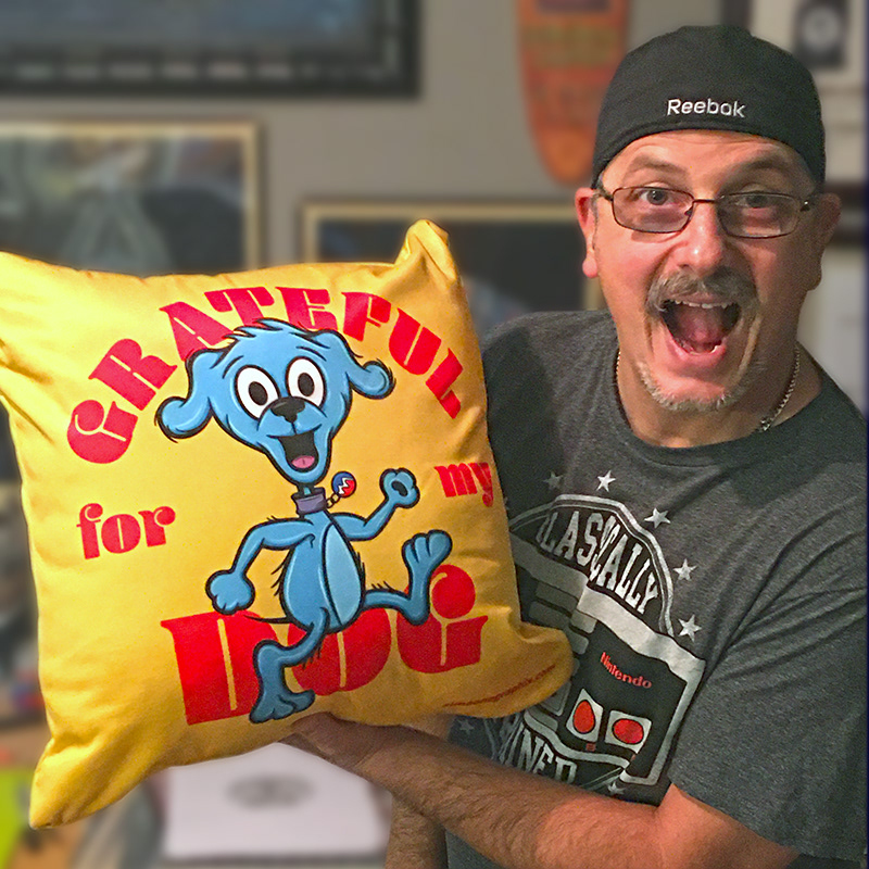 Artist Lou SImeone holding a pillow with his artwork on it