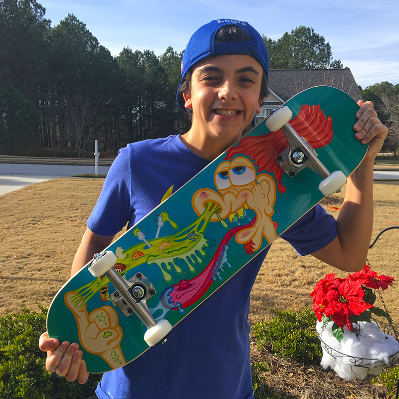 boy outside holding skateboard of nose picking artwork