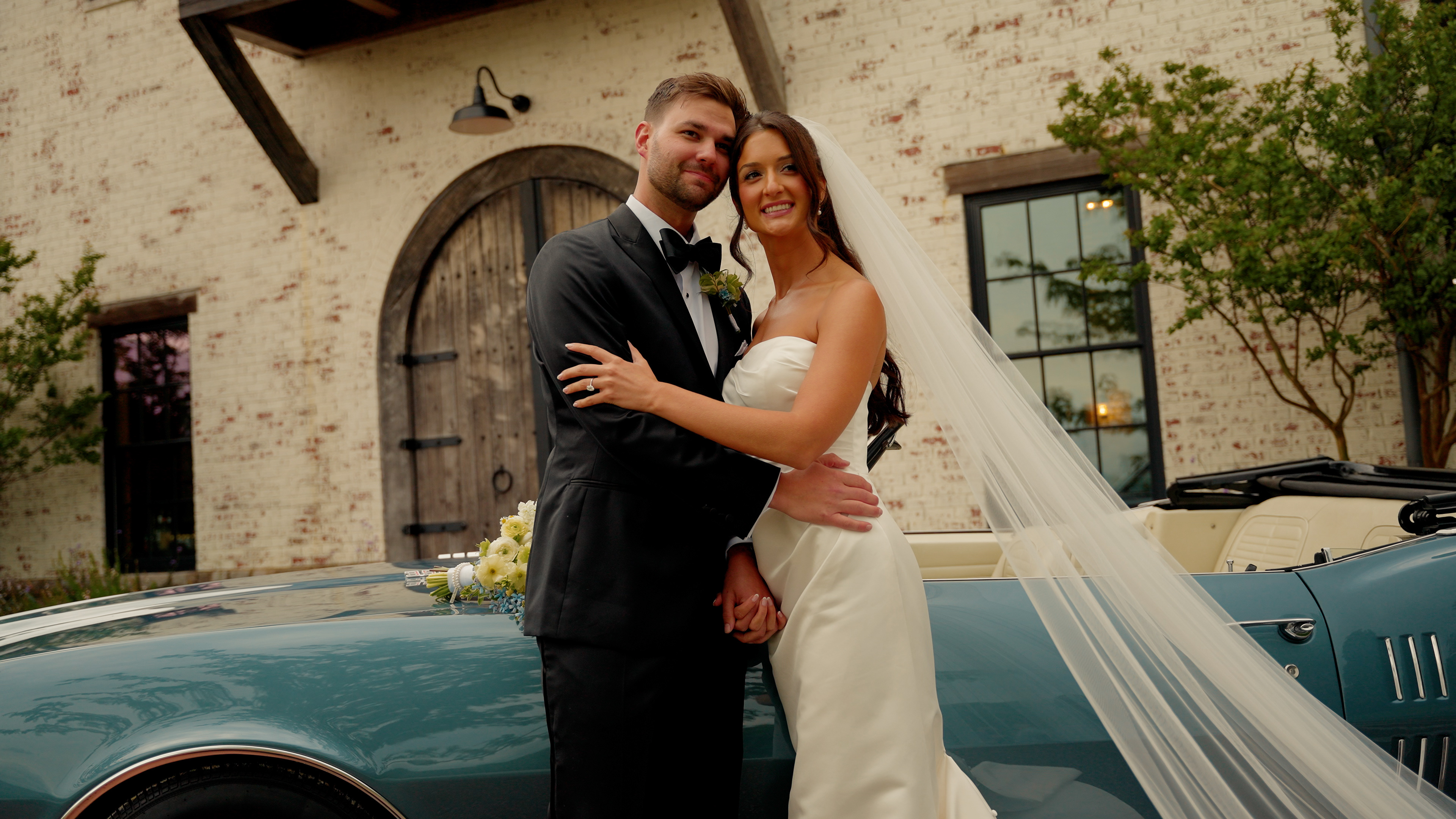 Bride and Groom hugging by classic sports car