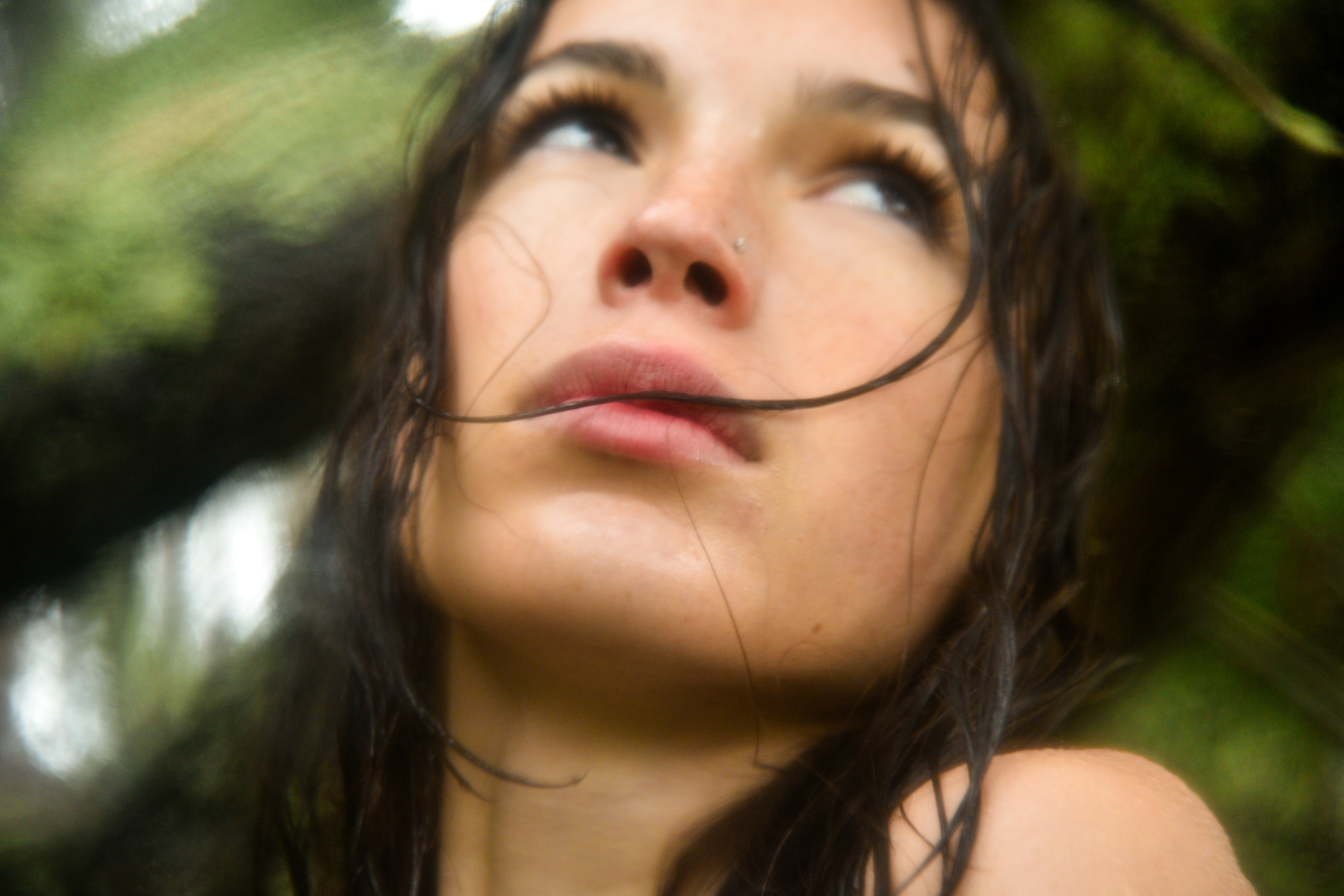 Looking up at the trees, my subject blends with the greenery behind her.