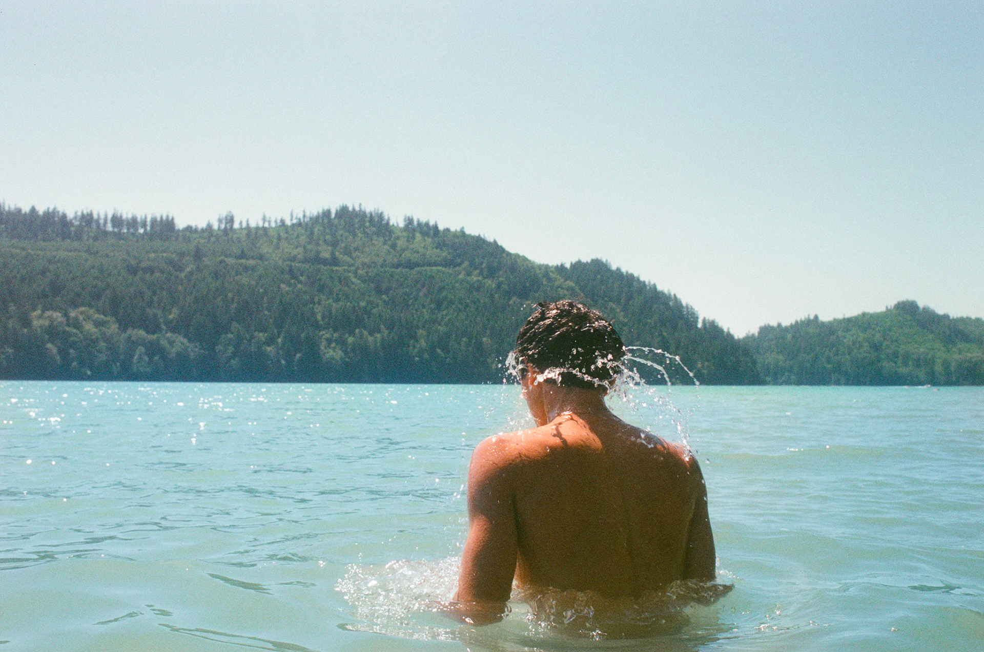 Caught in action, droplets cascade off of a swimmer, rejoining the larger lake.