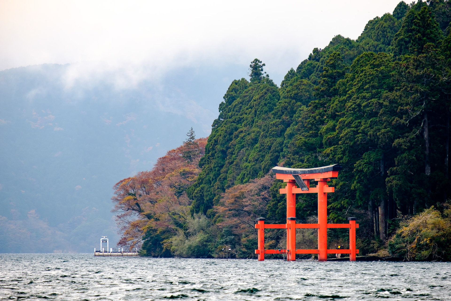 Red torii gate rising from Lake Ashi with misty mountains in Hakone