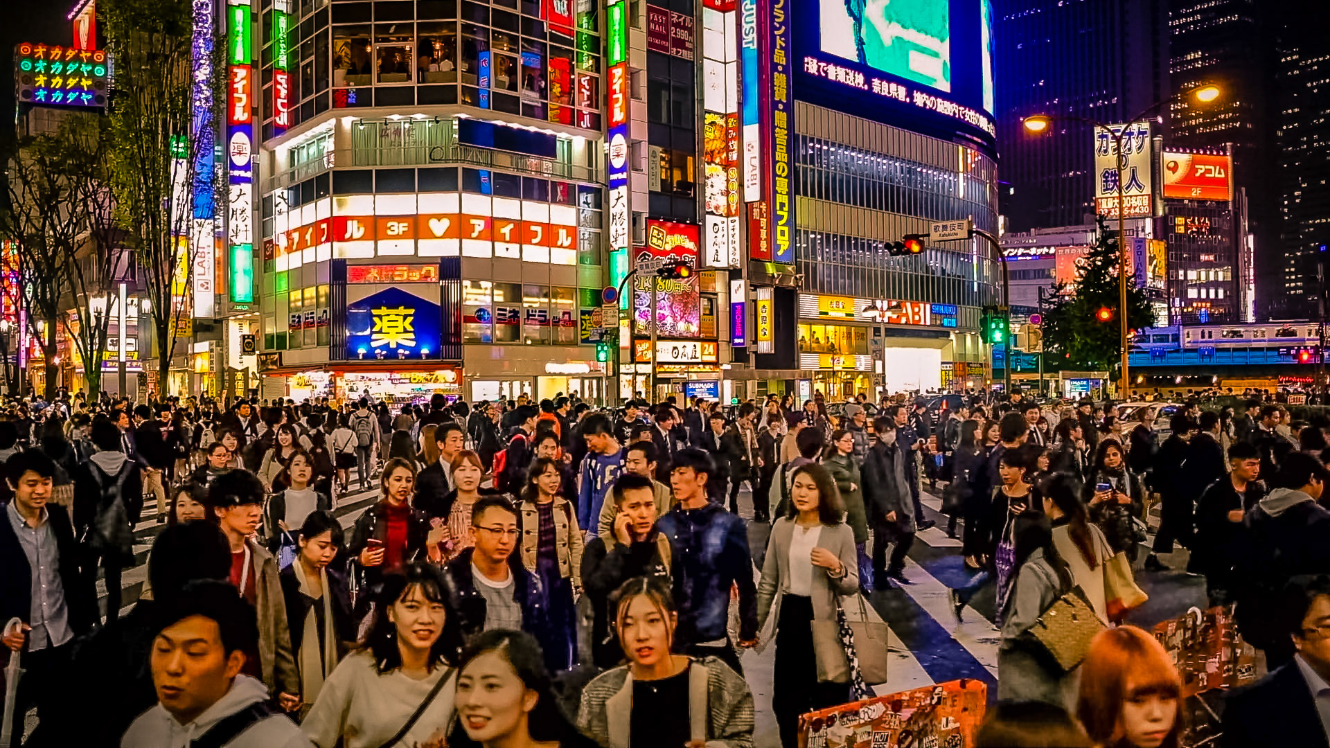 Busy Shinjuku crosswalk at night in Tokyo with neon lights and crowds of pedestrians, travel photography scene
