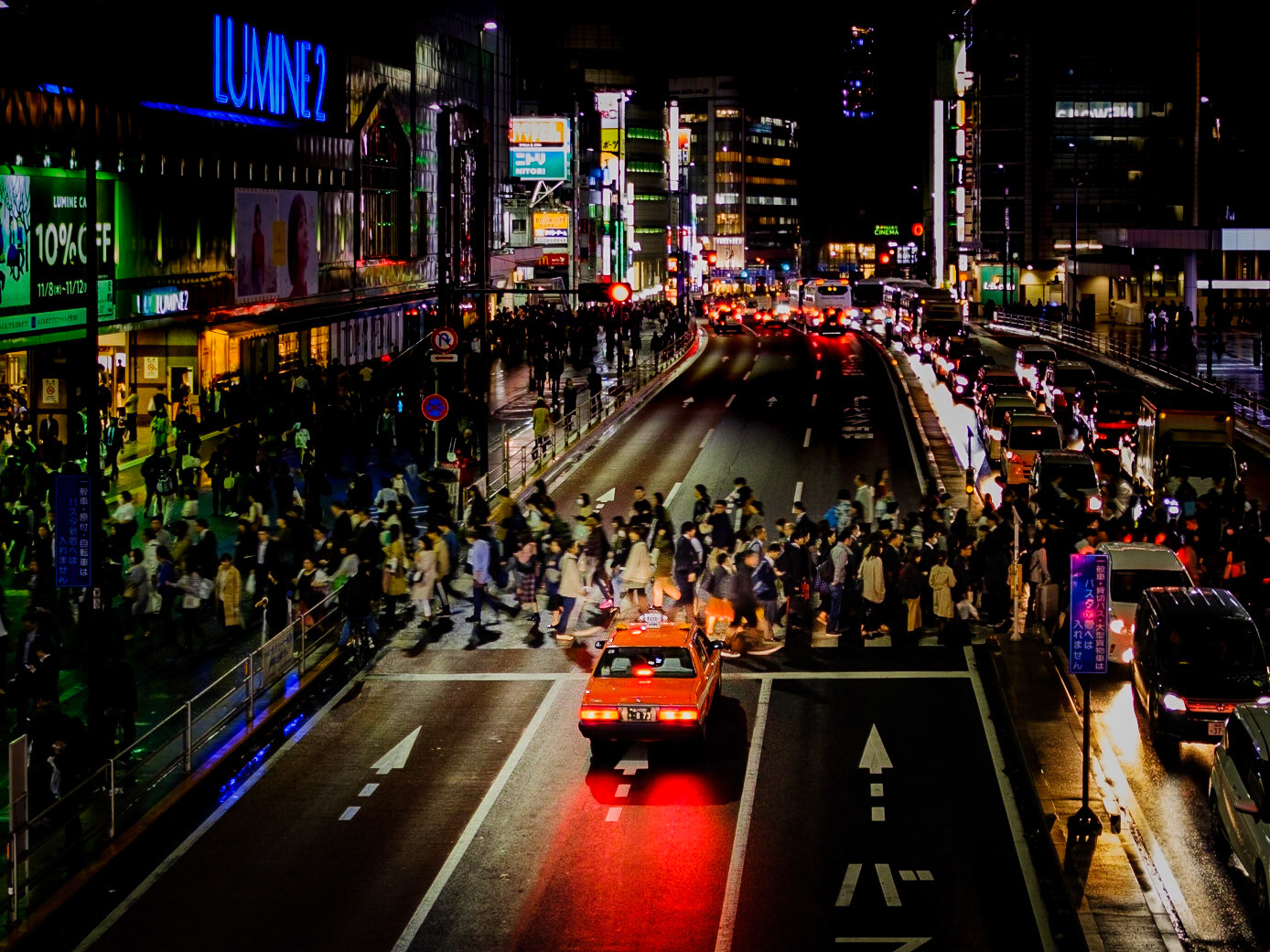 Crowds surge across the neon-lit crosswalk outside Shinjuku Station as taxis and buses stream through the night, capturing Tokyo’s unstoppable energy.