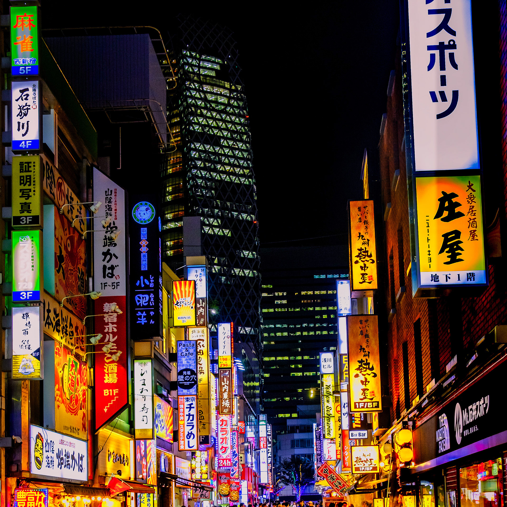 Shinjuku street in Tokyo at night with neon signs, crowds, and skyscrapers glowing in bright colors