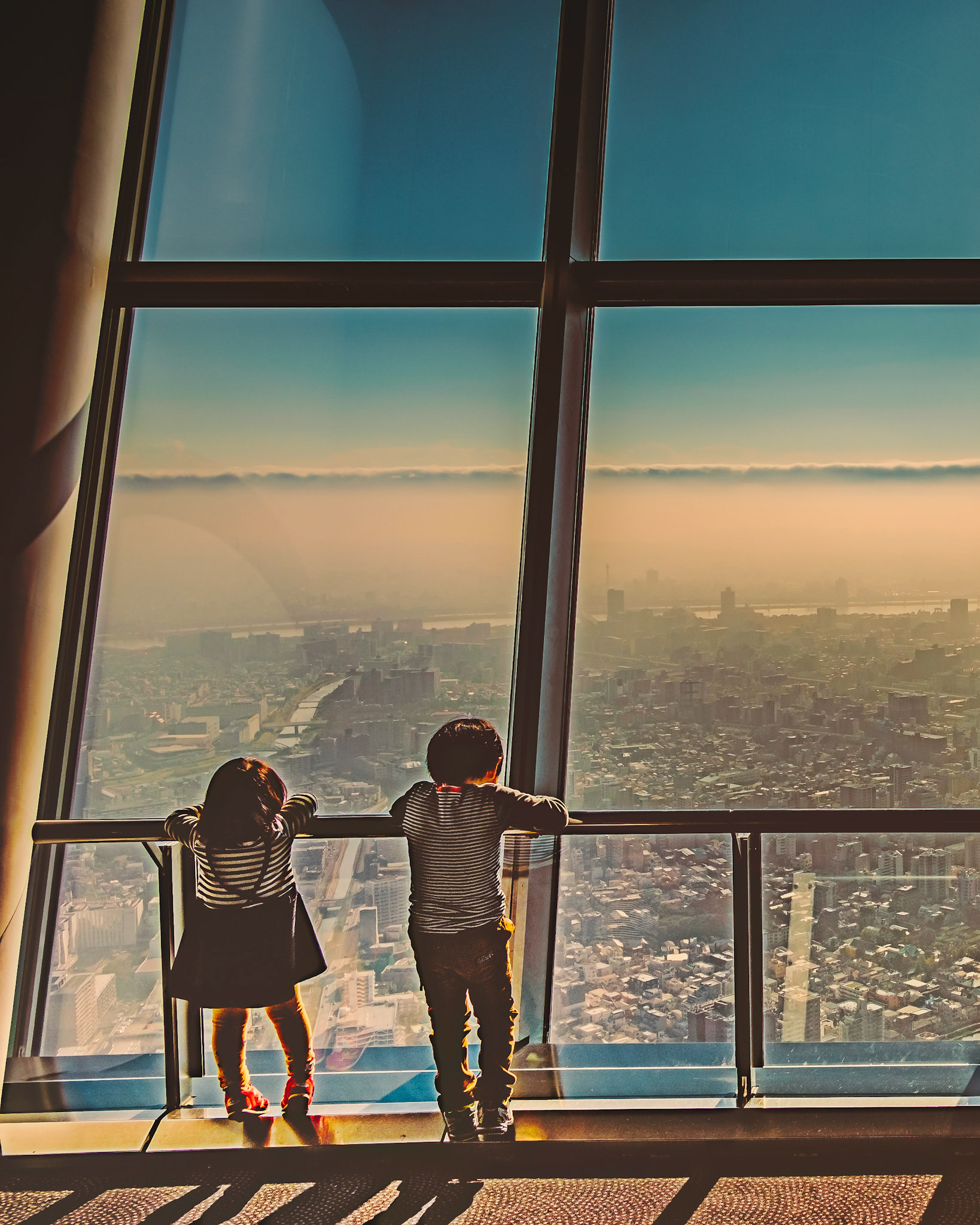 Afternoon at Tokyo Skytree — two children watching the city fade into golden light.