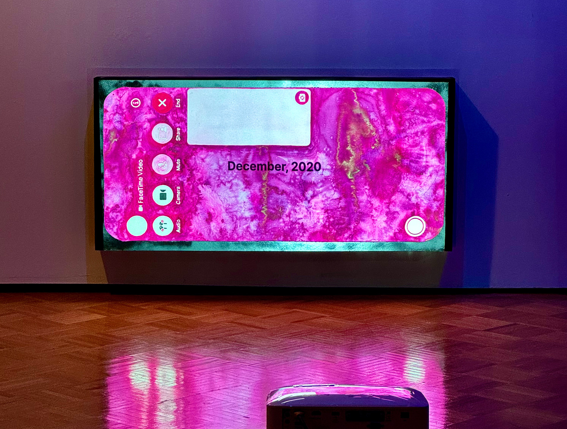 Facetime installation image: hot pink facetime screenshot with a slideshow of dates (November, 2020 to August 2021) projected onto the screen.