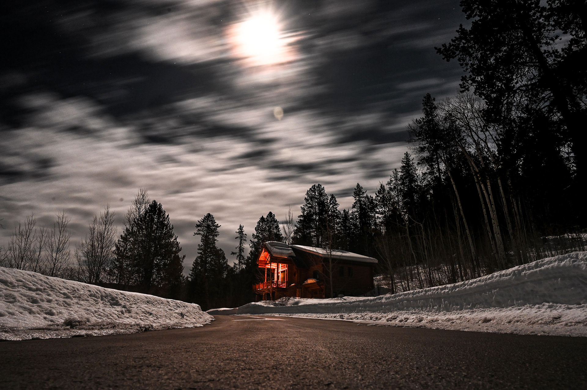 Long exposure image of a cabin in the woods with the clouds moving by quickly