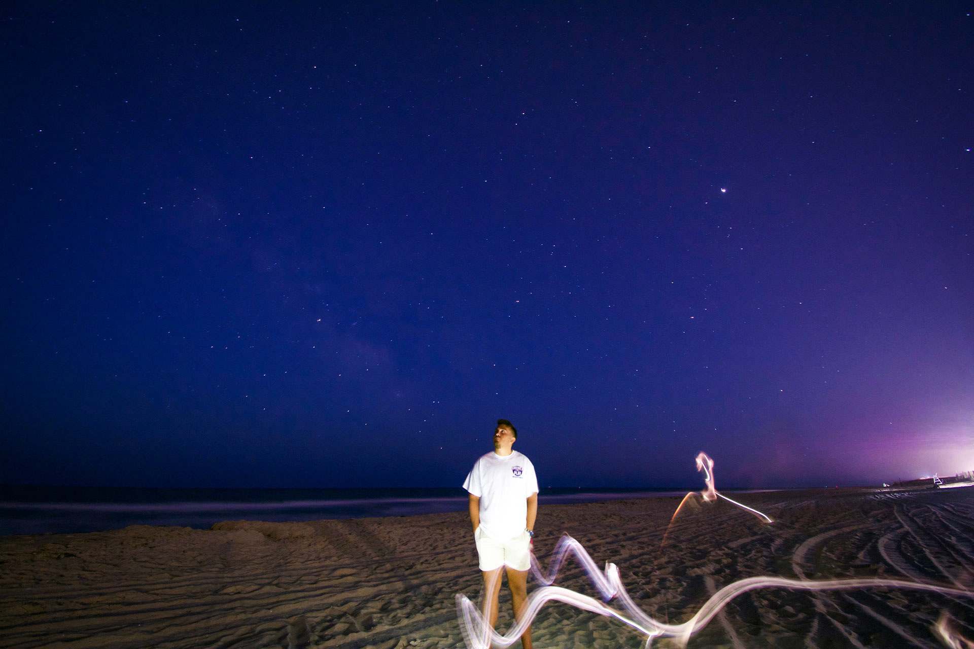 A man standing on the beach with ghostly figures around him