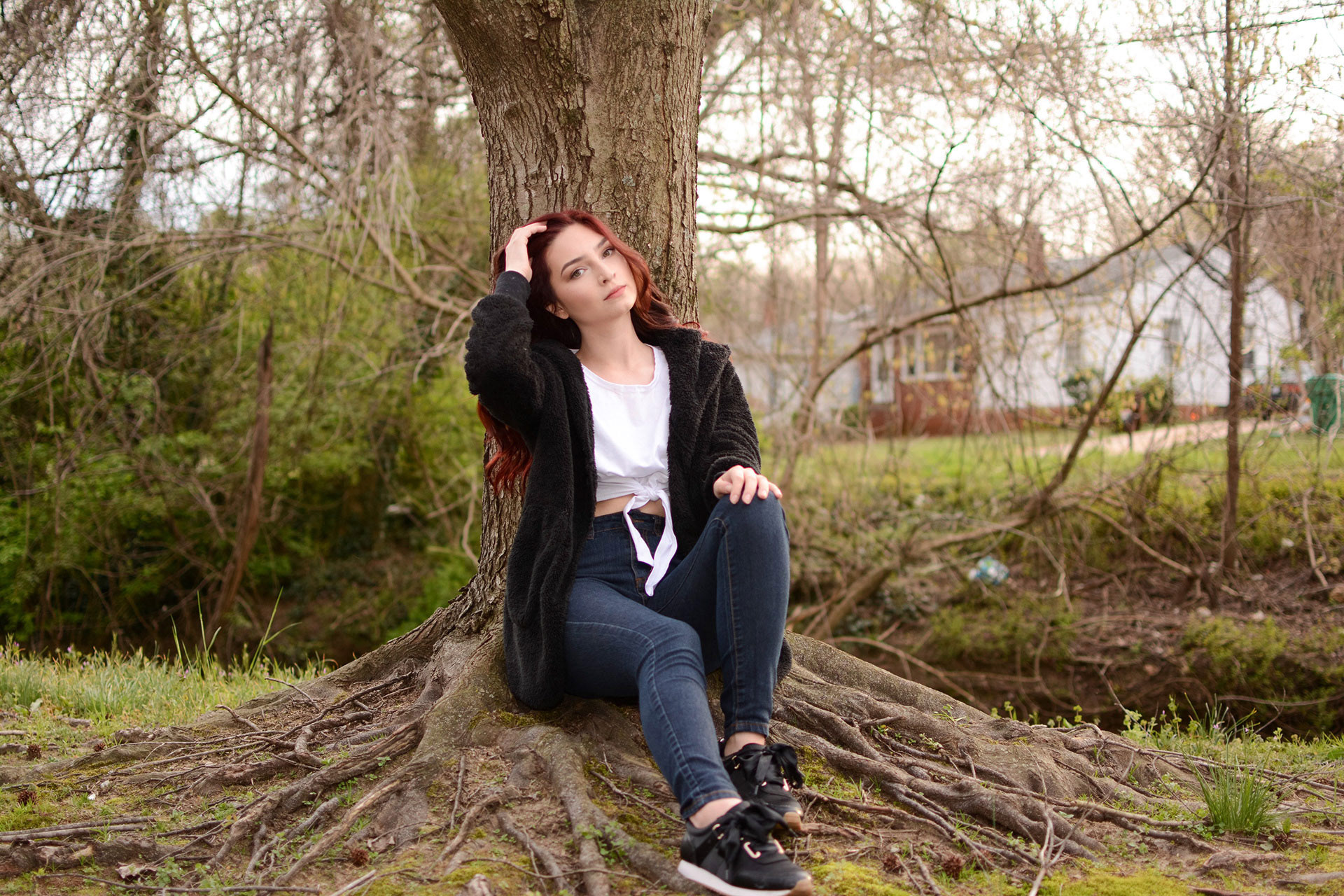Girl sitting under a tree fixing her hair