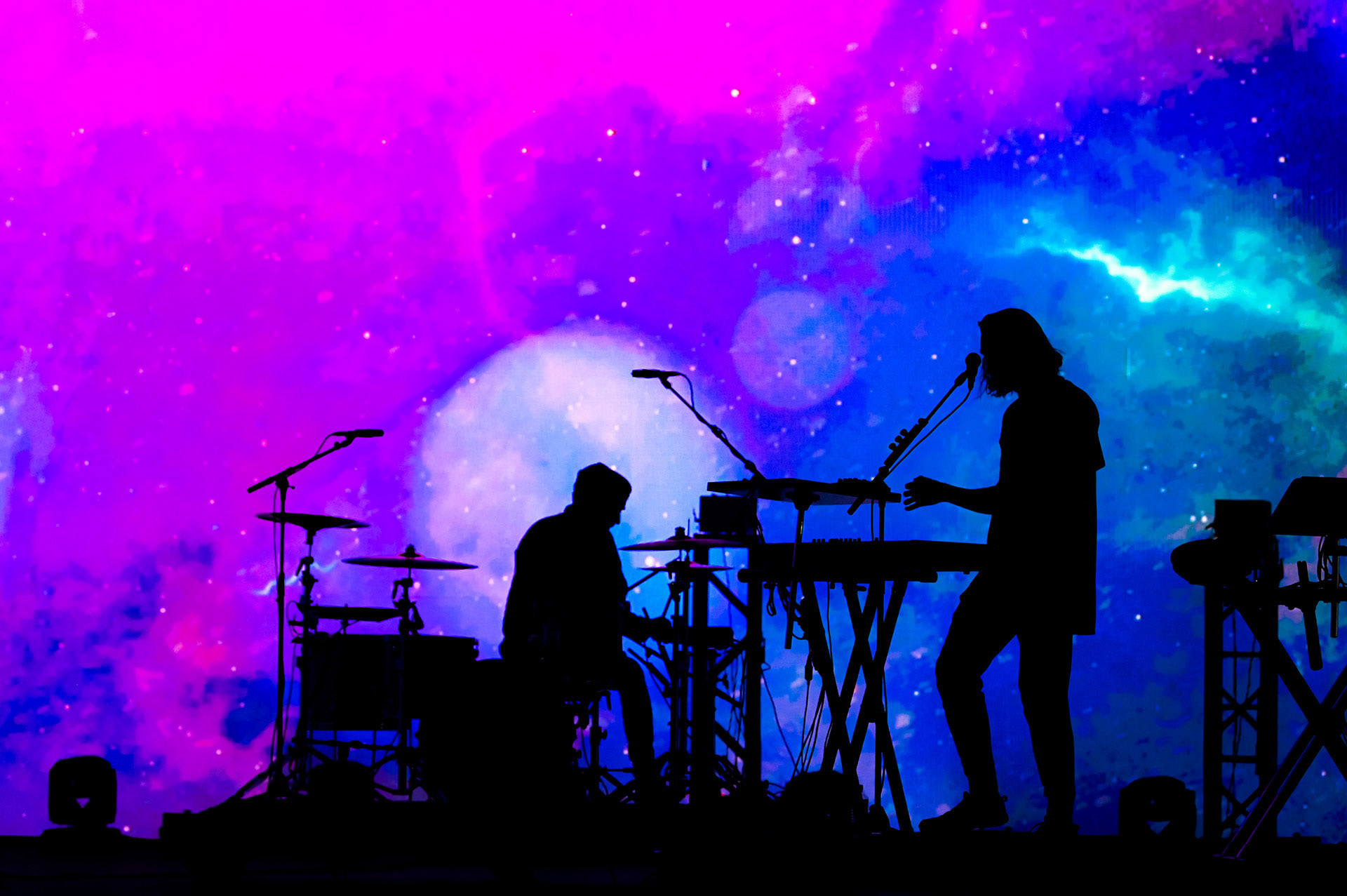 Silhouette of two musicians in front of an LED screen