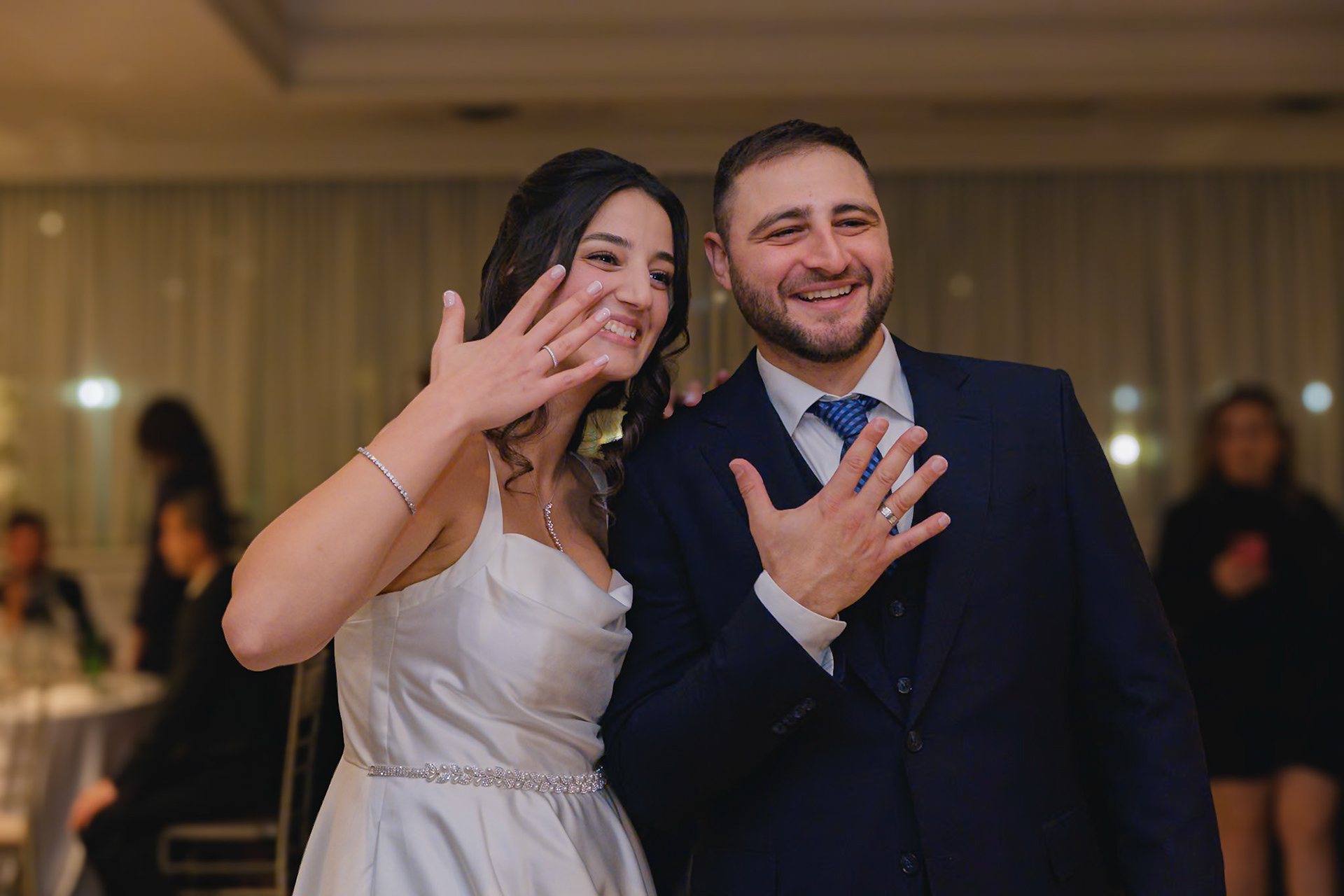 Bride and groom showing off their engagement rings with joy at Toronto celebration