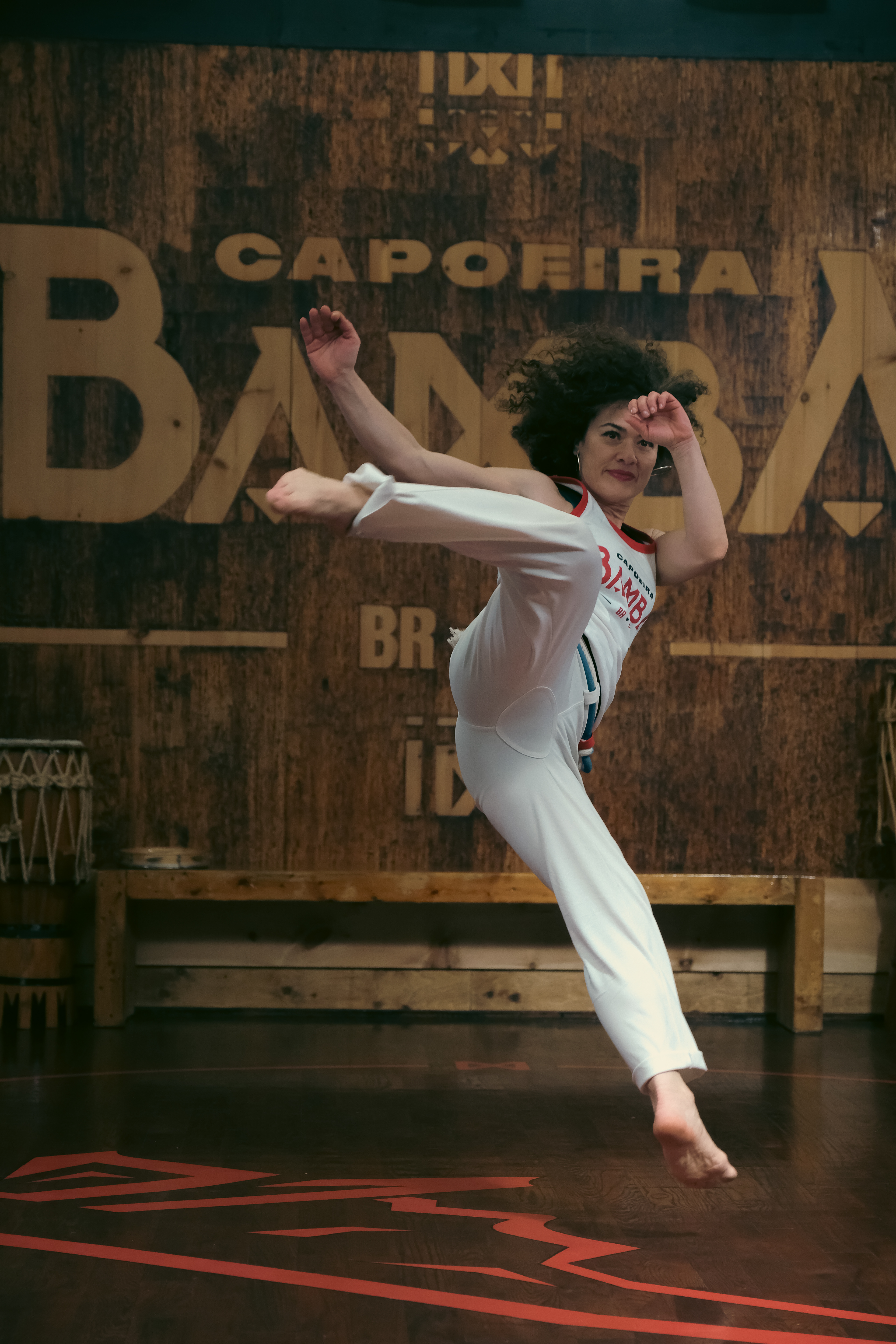 Capoeirista launching a spinning aerial kick over a red circle floor design.