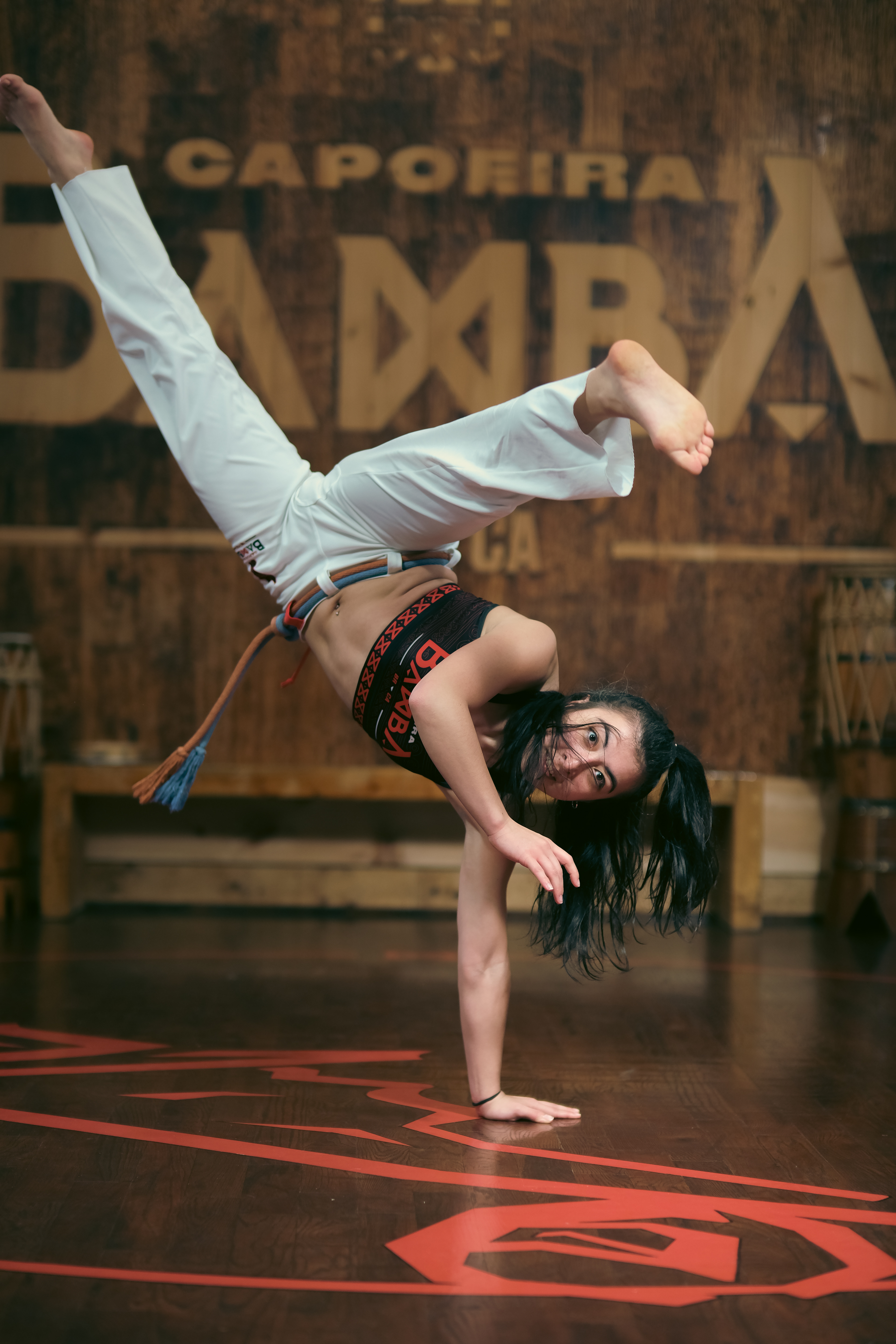 High-flying flip captured at the peak of motion inside the Capoeira training space.