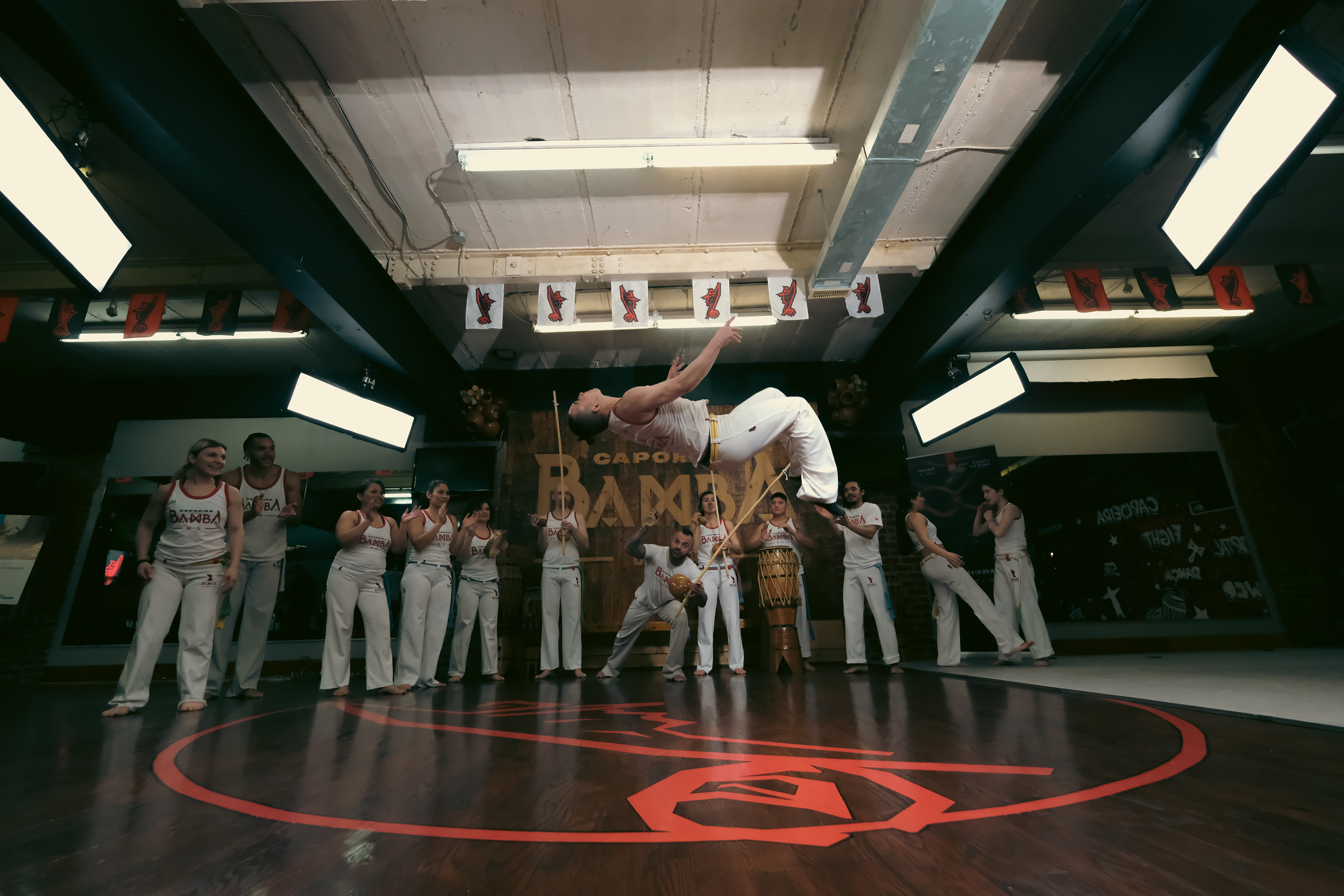 Capoeirista executing a high inverted flip with audience clapping in the background.